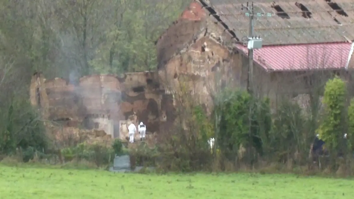 Zwei Beamte der Spurensicherung suchen in der Ruine der Scheune nach Hinweisen.
