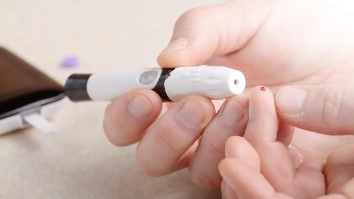 Man Pierce his fingertip before doing blood test with personal glucometer