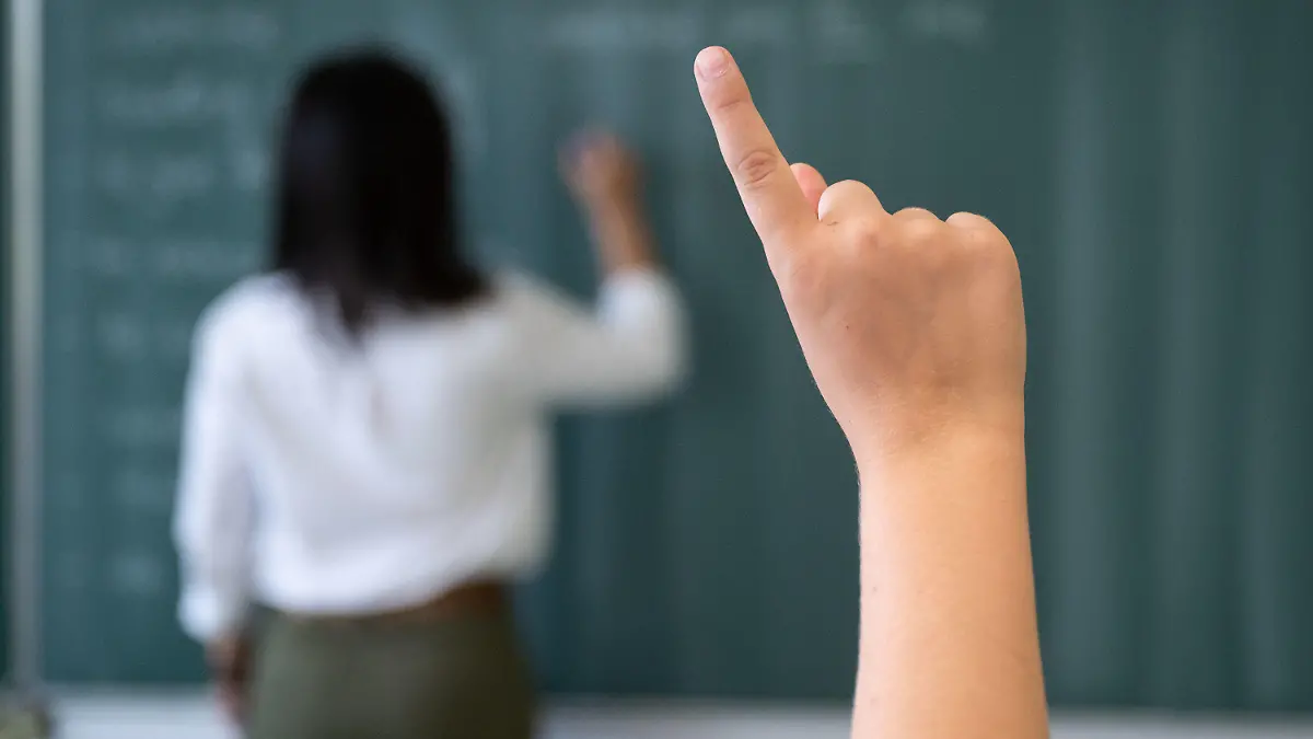 ARCHIV - 08.07.2020, Baden-Württemberg, Marbach am Neckar: Ein Schüler meldet sich während einer Unterrichtsstunde im Friedrich-Schiller Gymnasiums, während die Lehrerin an die Tafel schreibt. Mit Spannung werden die Ergebnisse der neuen Pisa-Studie erwartet. Was in der Studie getestet wird und warum sie eine so große Rolle spielt. Foto: Marijan Murat/dpa +++ dpa-Bildfunk +++