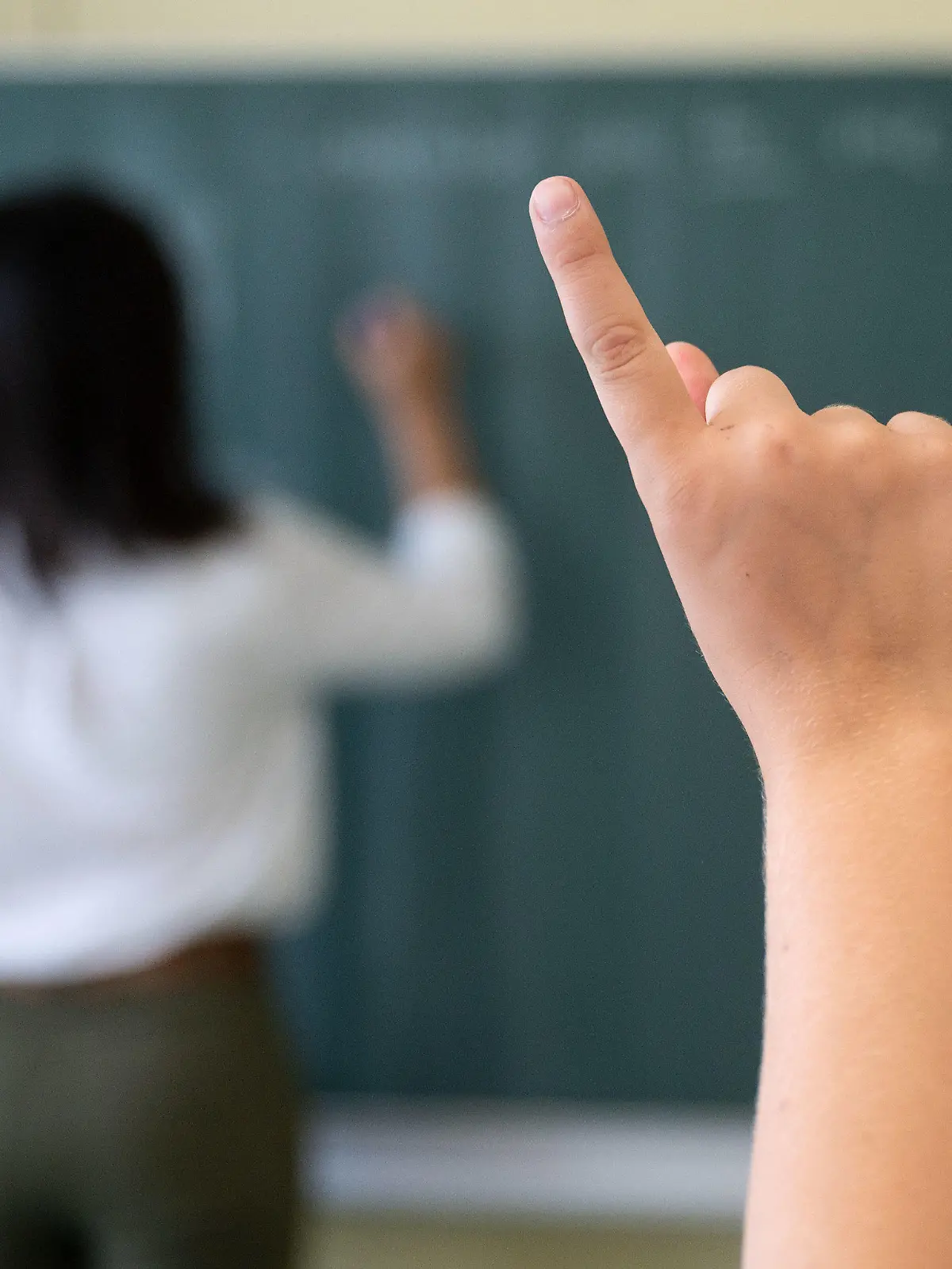 ARCHIV - 08.07.2020, Baden-Württemberg, Marbach am Neckar: Ein Schüler meldet sich während einer Unterrichtsstunde im Friedrich-Schiller Gymnasiums, während die Lehrerin an die Tafel schreibt. Mit Spannung werden die Ergebnisse der neuen Pisa-Studie erwartet. Was in der Studie getestet wird und warum sie eine so große Rolle spielt. Foto: Marijan Murat/dpa +++ dpa-Bildfunk +++
