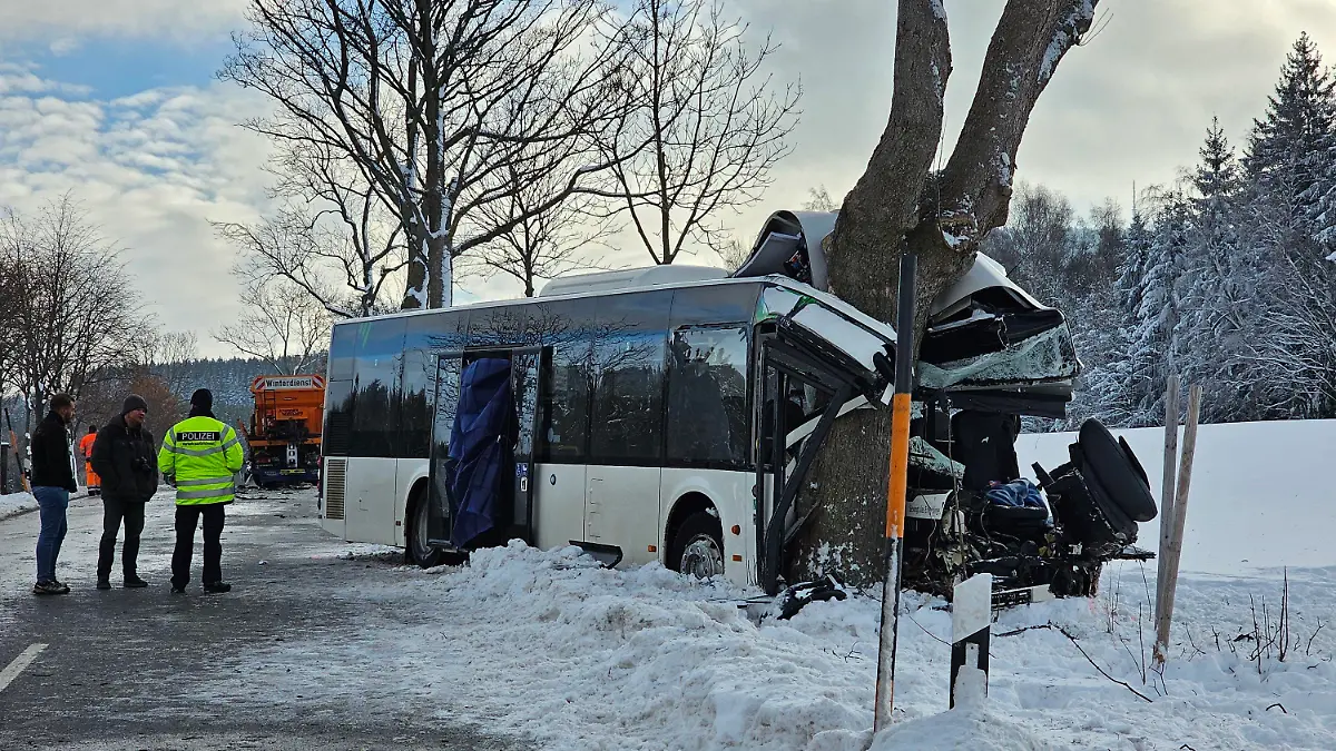 05.12.2023, Sachsen, Sehmatal-Cranzahl: Einsatzkräfte stehen an der Unfallstelle. Bei einem Unfall mit einem Schulbus in Sehmatal im Erzgebirge ist am Dienstagmorgen ein Kind getötet worden. Mindestens zehn weitere Schulkinder wurden verletzt. Zudem wurden zwei Erwachsene - darunter der Busfahrer - schwer verletzt. (Zu dpa: «Kind bei Schulbusunfall im Erzgebirge getötet - viele Verletzte») Foto: Mike Müller/dpa-Zentralbild/dpa +++ dpa-Bildfunk +++