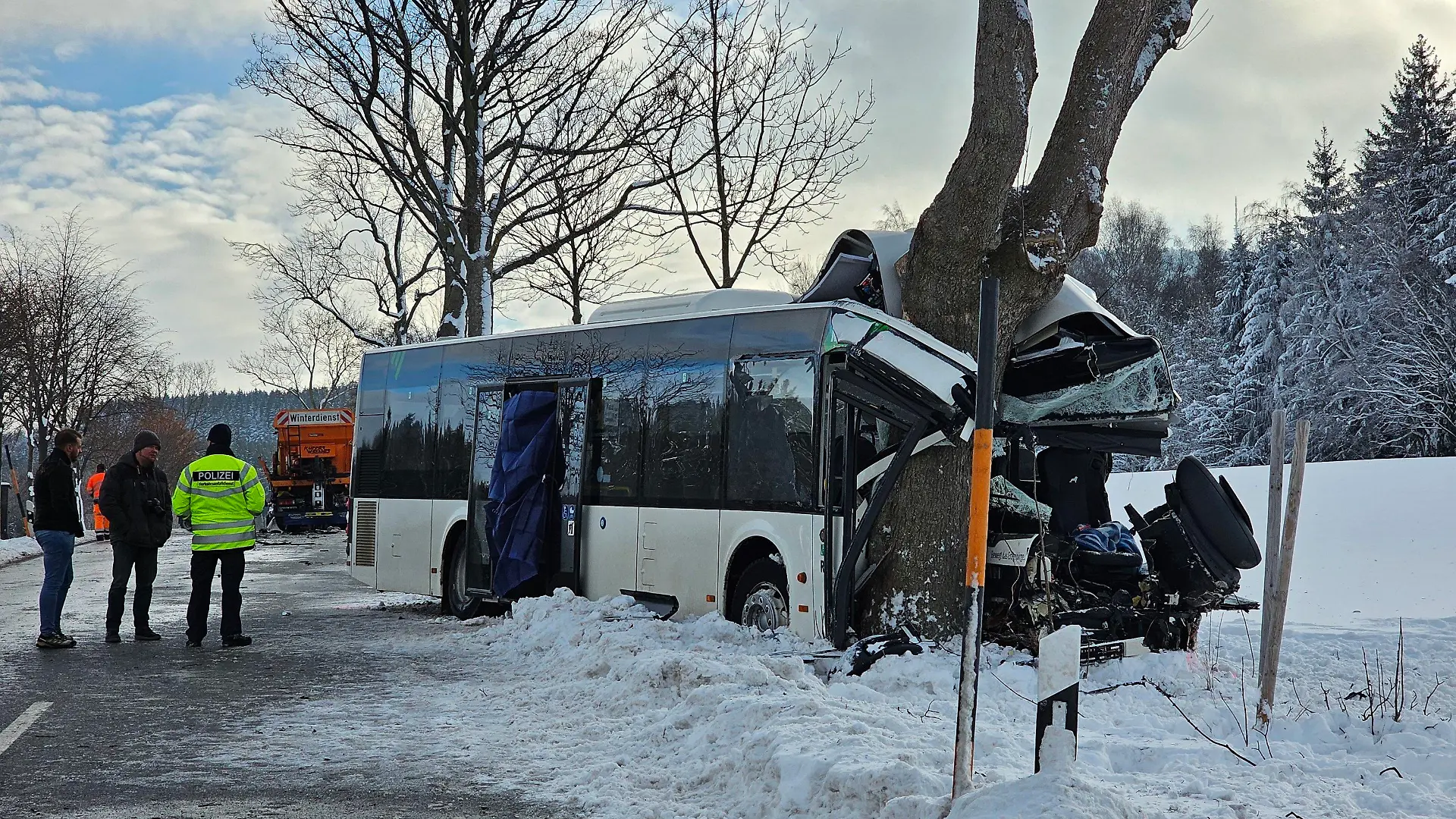 05.12.2023, Sachsen, Sehmatal-Cranzahl: Einsatzkräfte stehen an der Unfallstelle. Bei einem Unfall mit einem Schulbus in Sehmatal im Erzgebirge ist am Dienstagmorgen ein Kind getötet worden. Mindestens zehn weitere Schulkinder wurden verletzt. Zudem wurden zwei Erwachsene - darunter der Busfahrer - schwer verletzt. (Zu dpa: «Kind bei Schulbusunfall im Erzgebirge getötet - viele Verletzte») Foto: Mike Müller/dpa-Zentralbild/dpa +++ dpa-Bildfunk +++