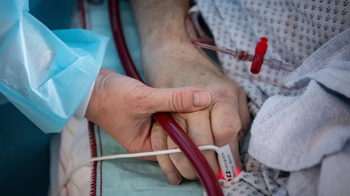 Eine Krankenschwester versorgt einen schwer an Corona erkrankten Patienten auf der Intensivstation des Klinikums in Fulda und hält dabei die Hand des Mannes. Viele Patienten mit schweren Verläufen liegen mehrere Wochen auf der Intensivstation, rund die Hälfte der künstlich beatmeten Patienten stirbt. (zu dpa "Sorgen um Engpässe in Kliniken und Altenheimen wegen Impfpflicht")