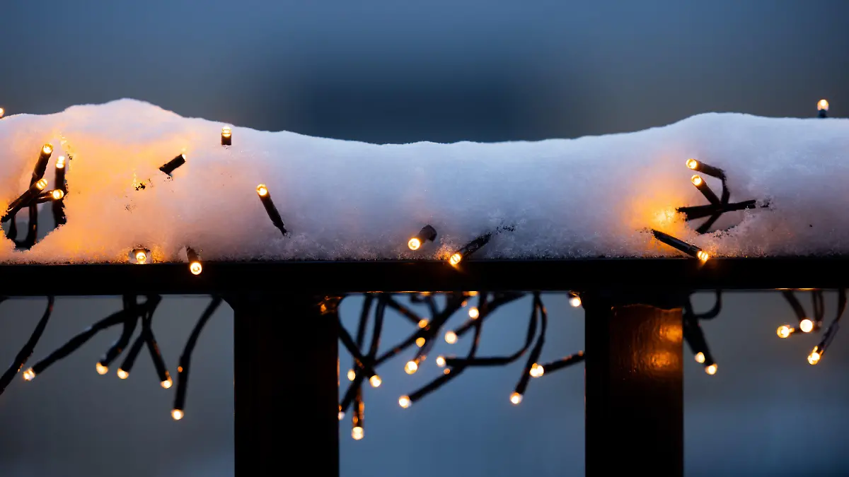 04.12.2023, Nordrhein-Westfalen, Köln: Schnee liegt auf über einer Lichterkette an einem Balkongeländer. Foto: Rolf Vennenbernd/dpa +++ dpa-Bildfunk +++