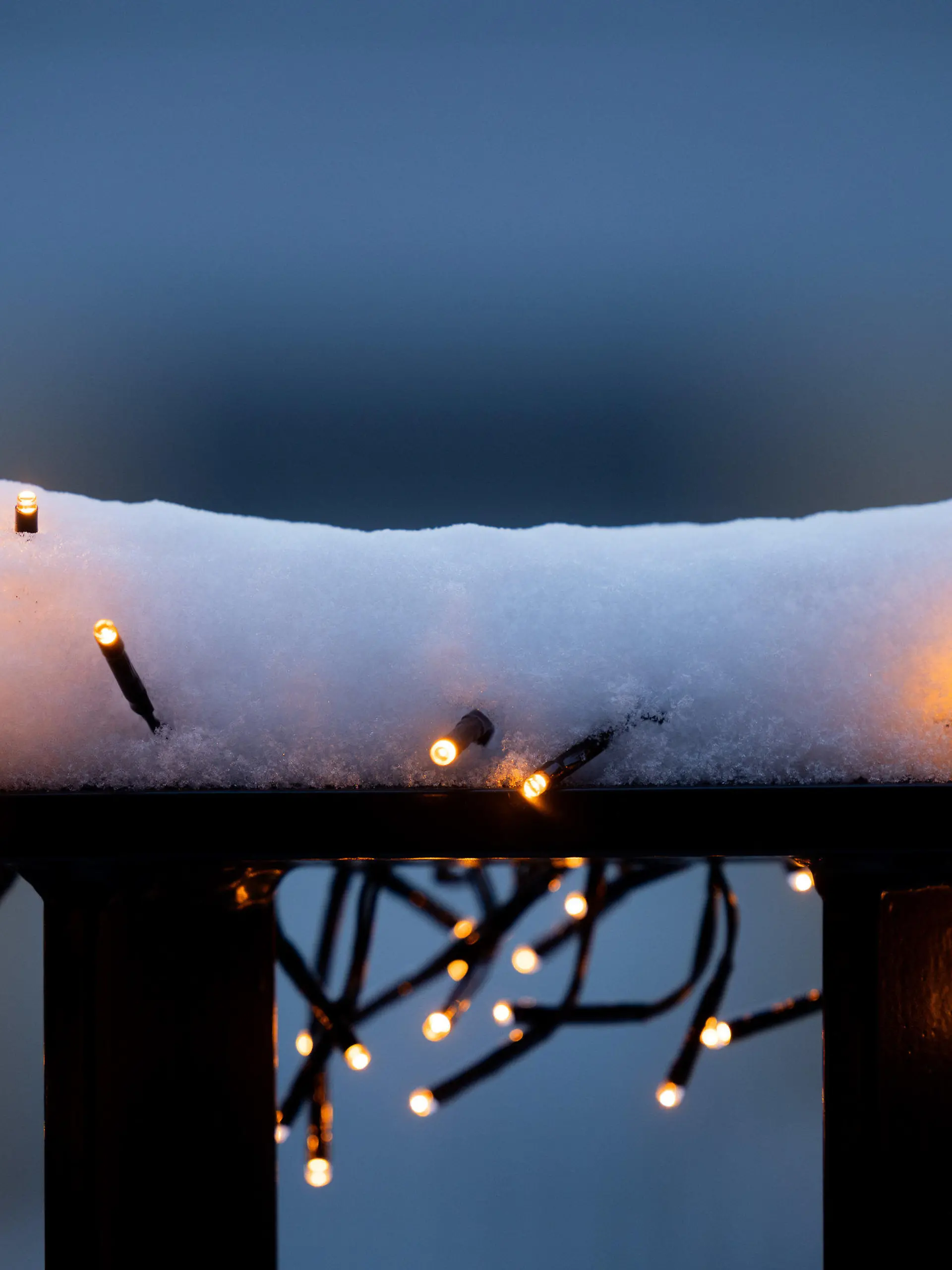 04.12.2023, Nordrhein-Westfalen, Köln: Schnee liegt auf über einer Lichterkette an einem Balkongeländer. Foto: Rolf Vennenbernd/dpa +++ dpa-Bildfunk +++