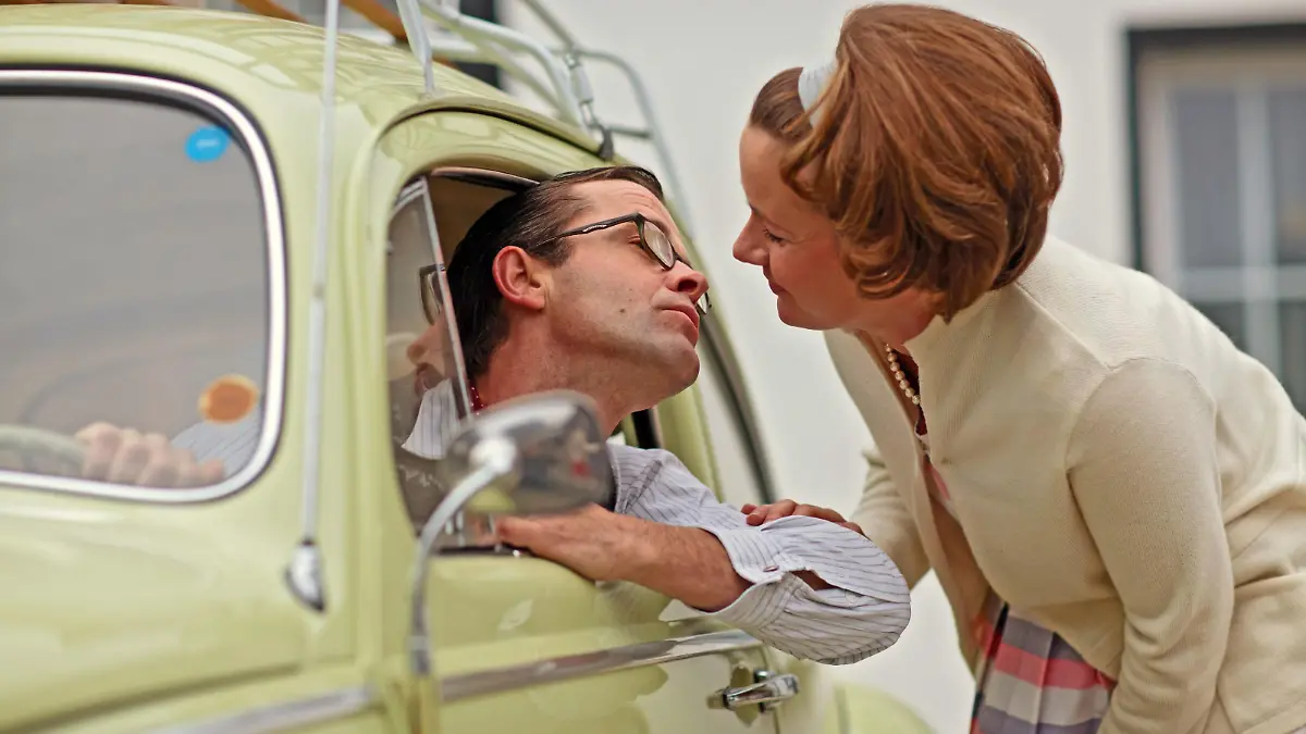 Familienfoto im Stil der 50er-Jahre. Der Volkswagen Baujahr 1955 steht im Mittelpunkt. Szene: Der Mann sitzt am Steuer seines Wagens und verabschiedet sich vor dem Einfamilienhaus von seiner Ehefrau mit einem Kuss. Aufnahme gestellt (model released) Deutschland 2008. Deutschland, 15.11.2008
