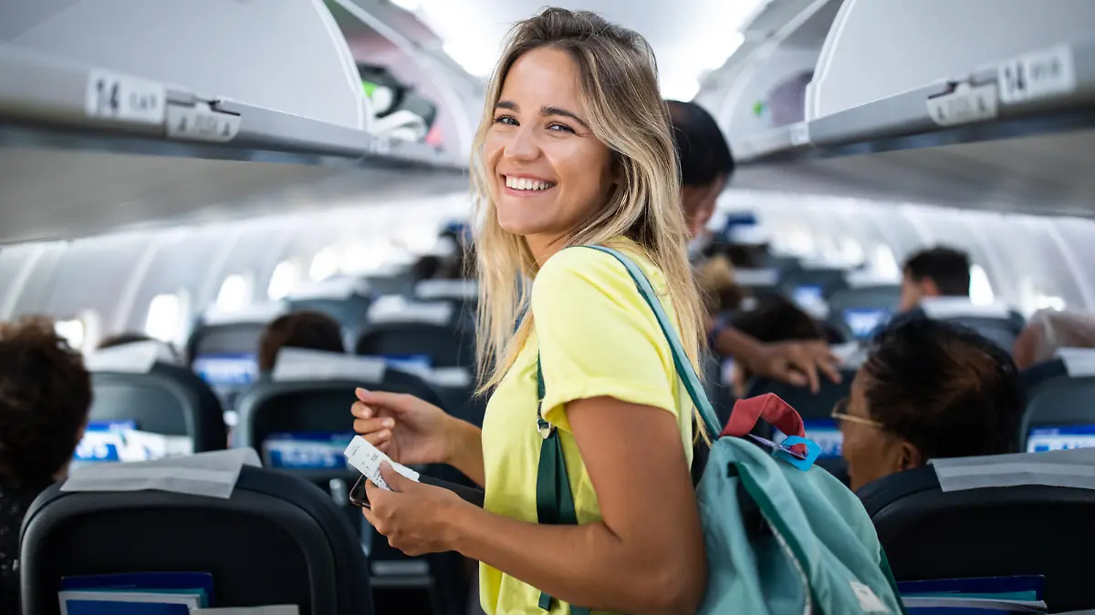 Happy woman boarding the airplane and looking at camera.