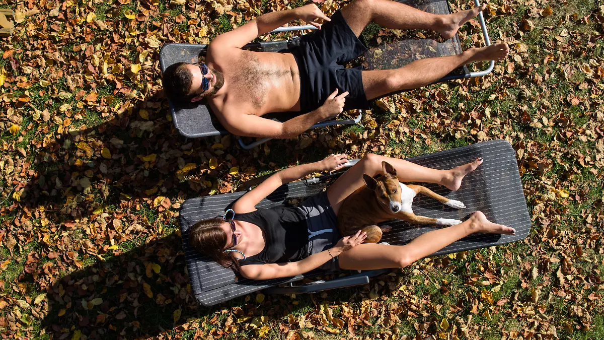 14.10.2018, Saarland, Saarbrücken: Ann-Kathrin und Patrick sonnen sich inmitten herbstlich bunter Blätter in ihrem Garten. Ungewöhnlich hohe Temperaturen laden auch im Oktober noch zum Sonnenbad ein. Foto: Oliver Dietze/dpa