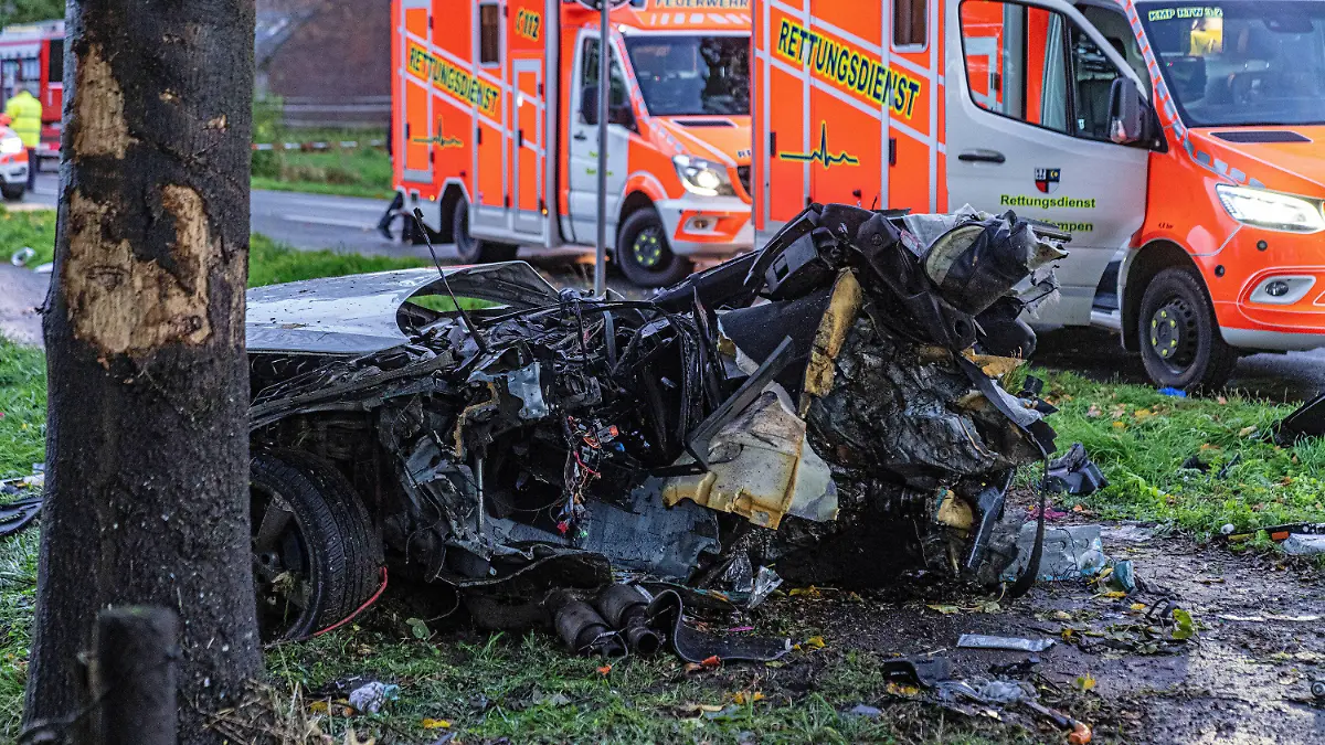 24.10.2022, Nordrhein-Westfalen, Rheurdt: Das Wrack eines Autos nach einem Unfall. Dahinter stehen Krankenwagen. Bei einem Aufprall eines Autos gegen einen Baum sind drei Menschen im Kreis Kleve ums Leben gekommen, darunter ein Kind und ein Säugling. Ein Mitfahrer habe lebensgefährliche Verletzungen erlitten, wie die Polizei am Montagabend mitteilte. Nach ersten Erkenntnissen der Ermittler war der Pkw aus unbekannter Ursache am Montagnachmittag bei Rheurdt-Schaephuysen von der Fahrbahn abgekommen und gegen den Baum geprallt. Foto: Arnulf Stoffel/dpa +++ dpa-Bildfunk +++