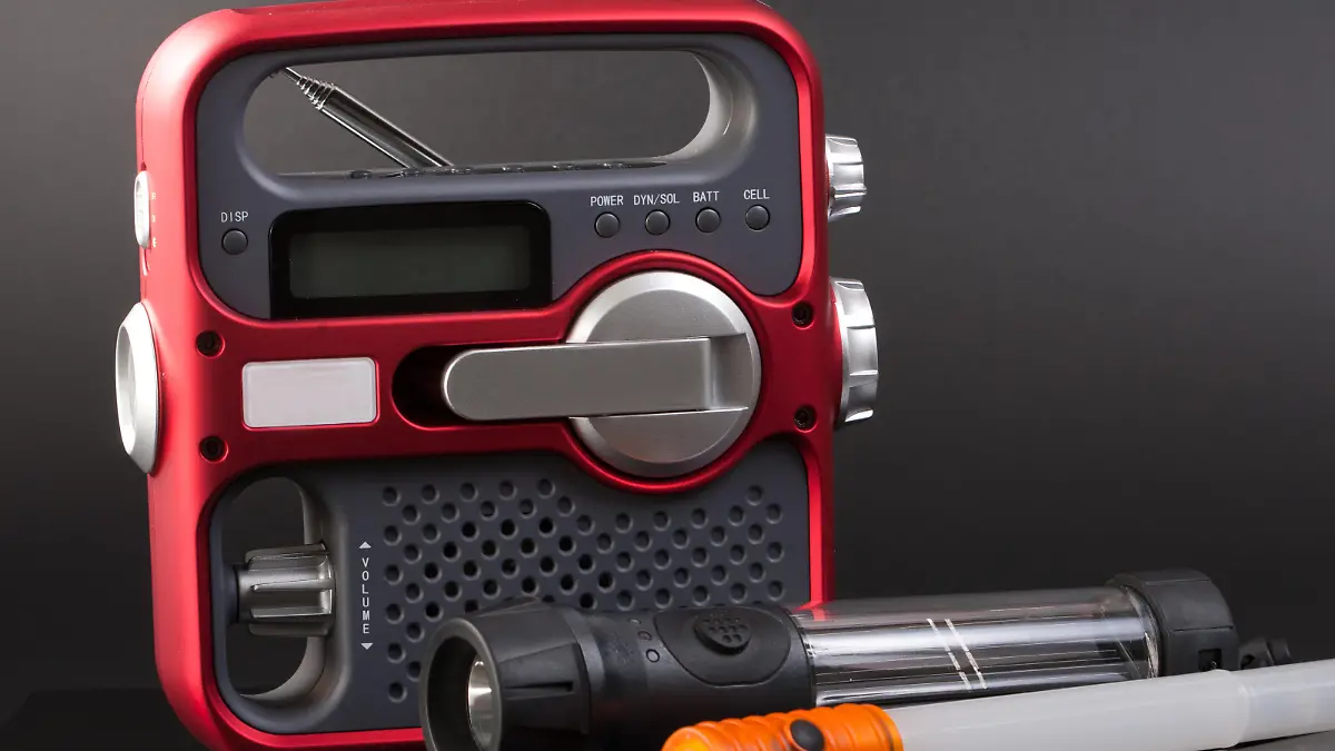 A handcrank/solar emergency radio, solar flashlight, and blinking light stick. Isolated on black.
