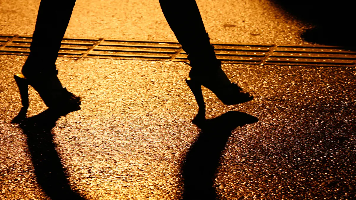 Junge Japanerin alleine auf einer regennassen Strasse in Shinjuku unterwegs, umgeben von dunklen Schatten hastet sie durch die Nacht. Shinjuku ist bekannt als Einkaufsmeile und Amuesierviertel mit Clubs, Bars, Restaurants, Karaoke, Shops und Rotlichtbezirk.