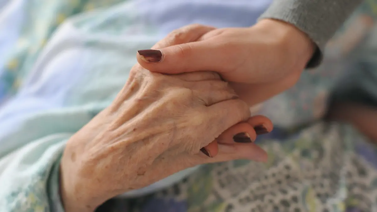 ARCHIV - Eine junge Frau hält am 15.02.2011 die Hände einer alten Frau, die in einem Rollstuhl in einem Seniorenheim sitzt. Die gesetzliche Darlehensregelung für pflegende Angehörige, die berufstätig sind, ist nach Ansicht der Deutschen Stiftung Patientenschutz gescheitert. (zu dpa «Stiftung: Pflegedarlehen funktionieren nicht» vom 27.01.2018) Foto: Patrick Pleul/dpa-Zentralbild/dpa +++ dpa-Bildfunk +++