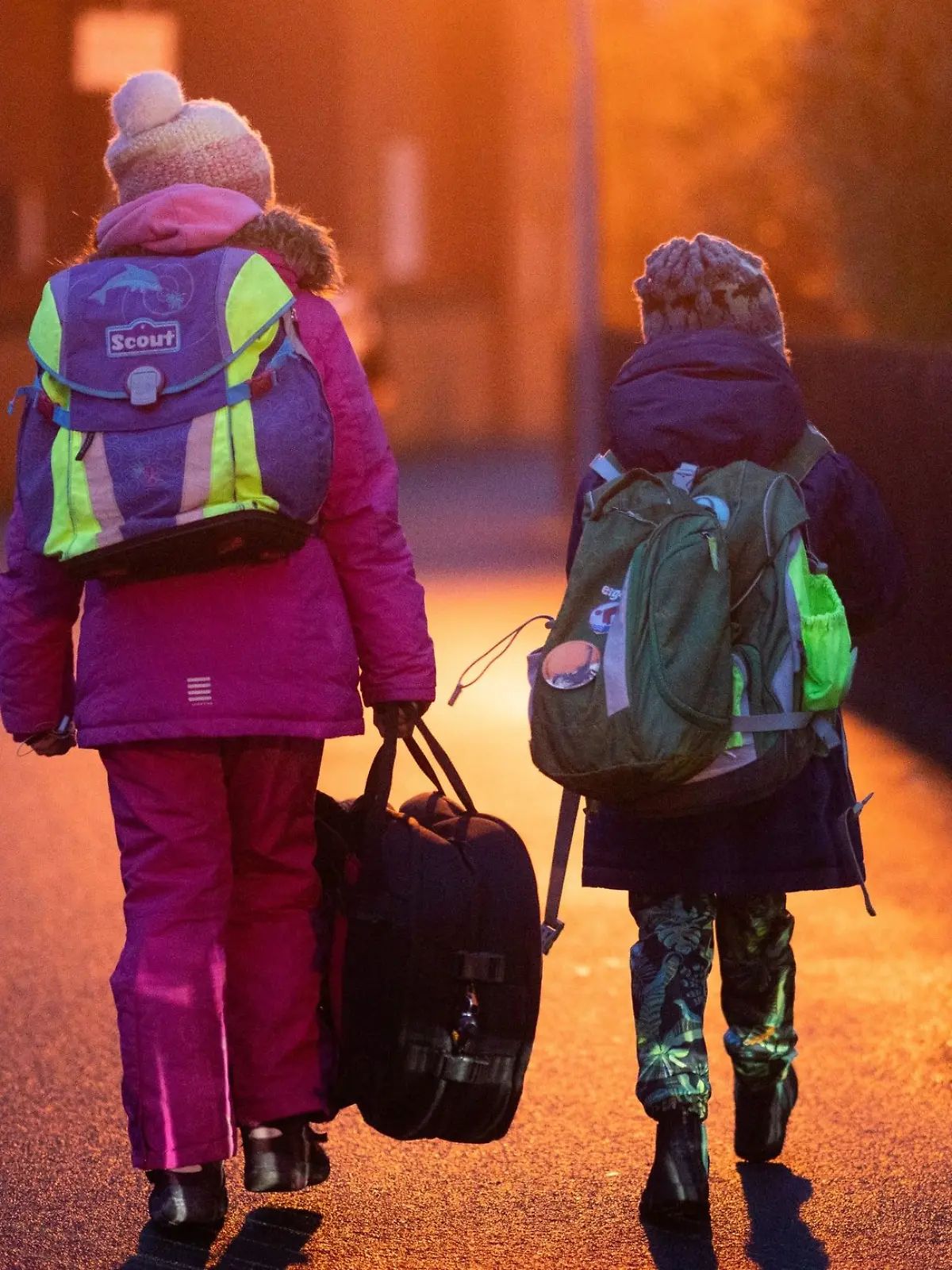 Zwei Schüler gehen am frühen Morgen auf dem Schulweg zu ihrer Grundschule in der Region Hannover.