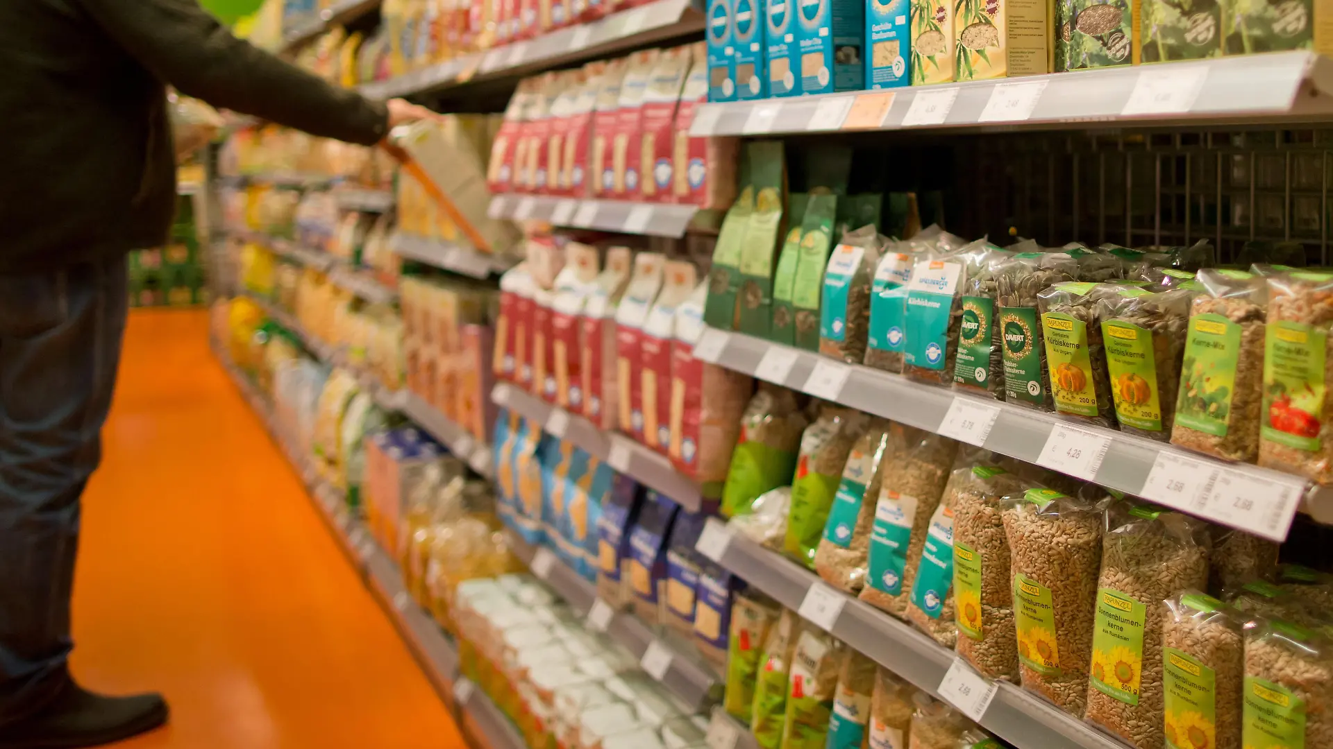 Ein Kunde greift nach ein Bioprodukt in einem Regal in einem Biosupermarkt am 04.02.2016 in Nürnberg (Bayern). Foto: Daniel Karmann/dpa ++