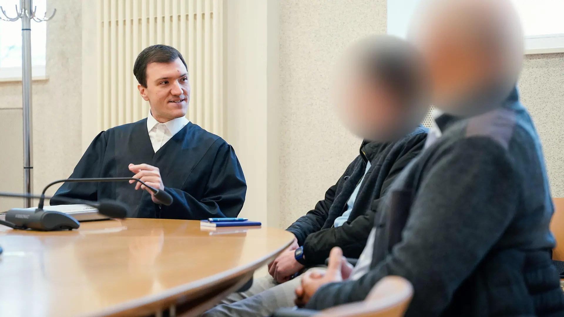 07.12.2023, Baden-Württemberg, Mannheim: Rechtsanwalt Timo van der Does (l) spricht mit den beiden Angeklagten im Verhandlungssaal des Amtsgerichts. Sie sollen getrennt voneinander und zu unterschiedlichen Zeitpunkten Pferde unter anderem mit einer Reitgerte oder der flachen Hand geschlagen haben. Einer soll einem Pferd zudem einen mit leeren Konserven- beziehungsweise Getränkedosen gefüllten Jutesack angebunden und so das Wohlbefinden des Tieres durch die lauten Klappergeräusche «nicht unerheblich beeinträchtigt» haben. Foto: Uwe Anspach/dpa - ACHTUNG: Person(en) wurde(n) aus rechtlichen Gründen gepixelt +++ dpa-Bildfunk +++