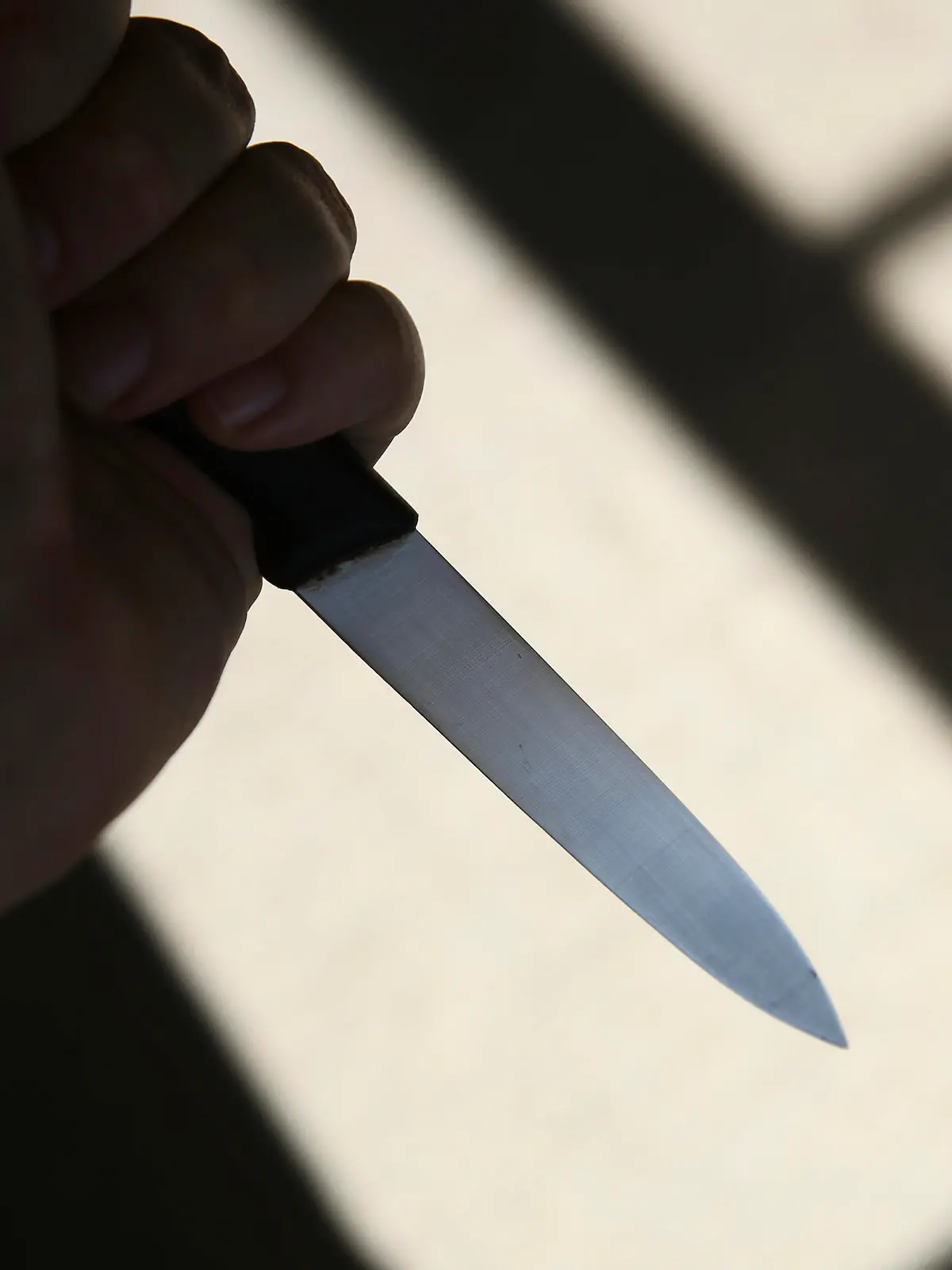 A hand holding a knife in shadow. This image can be used to represent stabbing or murder.