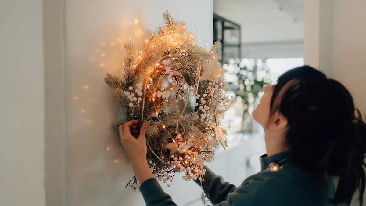 Photo of a young woman decorating the living room of her apartment; getting ready for the upcoming holiday season.