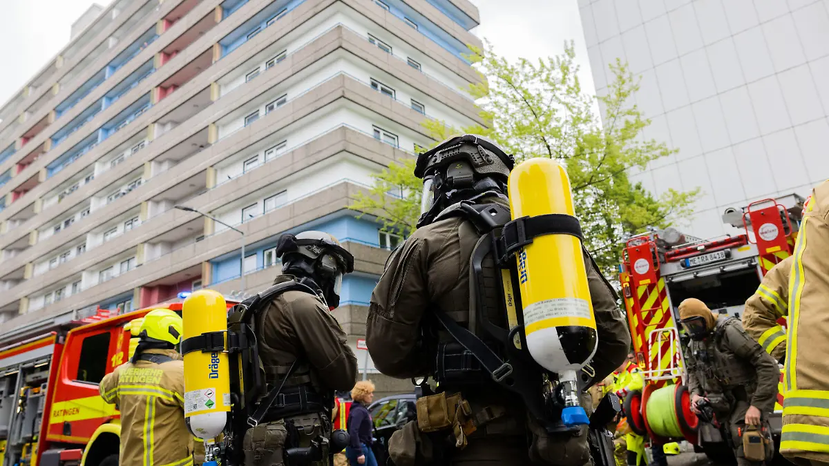 ARCHIV - 11.05.2023, Nordrhein-Westfalen, Ratingen: Polizeibeamte mit Gasmasken und Feuerwehrleute stehen vor einem Hochhaus in Ratingen. Dem Angeklagten wird neunfacher versuchter Mord vorgeworfen. Er soll Polizisten, Feuerwehrleute und Rettungssanitäter mit Benzin überschüttet und angezündet haben. (zu dpa «Neunfacher Mordversuch: Prozess um Explosion in Ratingen beginnt») Foto: Rolf Vennenbernd/dpa +++ dpa-Bildfunk +++