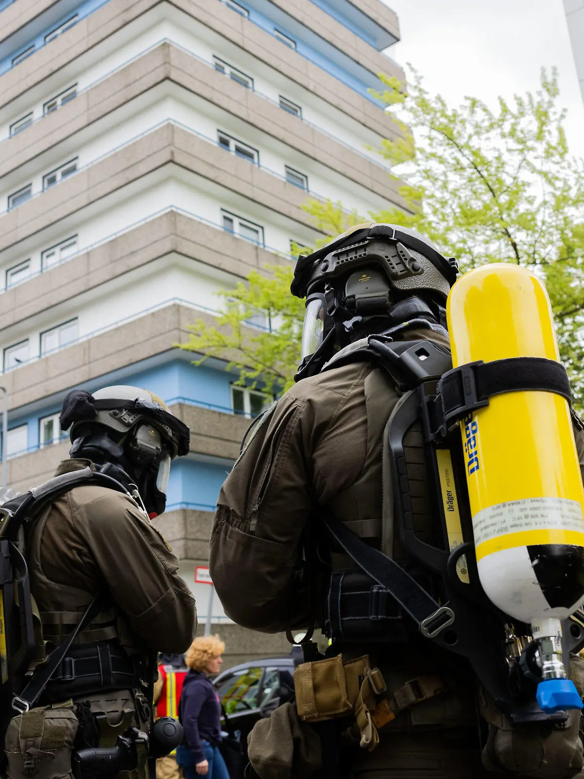 ARCHIV - 11.05.2023, Nordrhein-Westfalen, Ratingen: Polizeibeamte mit Gasmasken und Feuerwehrleute stehen vor einem Hochhaus in Ratingen. Dem Angeklagten wird neunfacher versuchter Mord vorgeworfen. Er soll Polizisten, Feuerwehrleute und Rettungssanitäter mit Benzin überschüttet und angezündet haben. (zu dpa «Neunfacher Mordversuch: Prozess um Explosion in Ratingen beginnt») Foto: Rolf Vennenbernd/dpa +++ dpa-Bildfunk +++