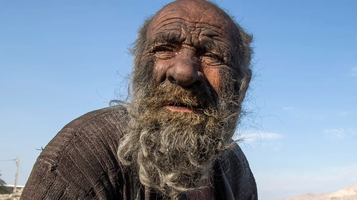 (FILES) In this file photo taken on December 28, 2018 Amou Haji (uncle Haji) sits on the outskirts of the village of Dezhgah in the Dehram district of the southwestern Iranian Fars province. - An Iranian dubbed the "dirtiest man in the world" for not taking a shower for decades has died at the age of 94, state media said on October 25, 2022. (Photo by AFP)