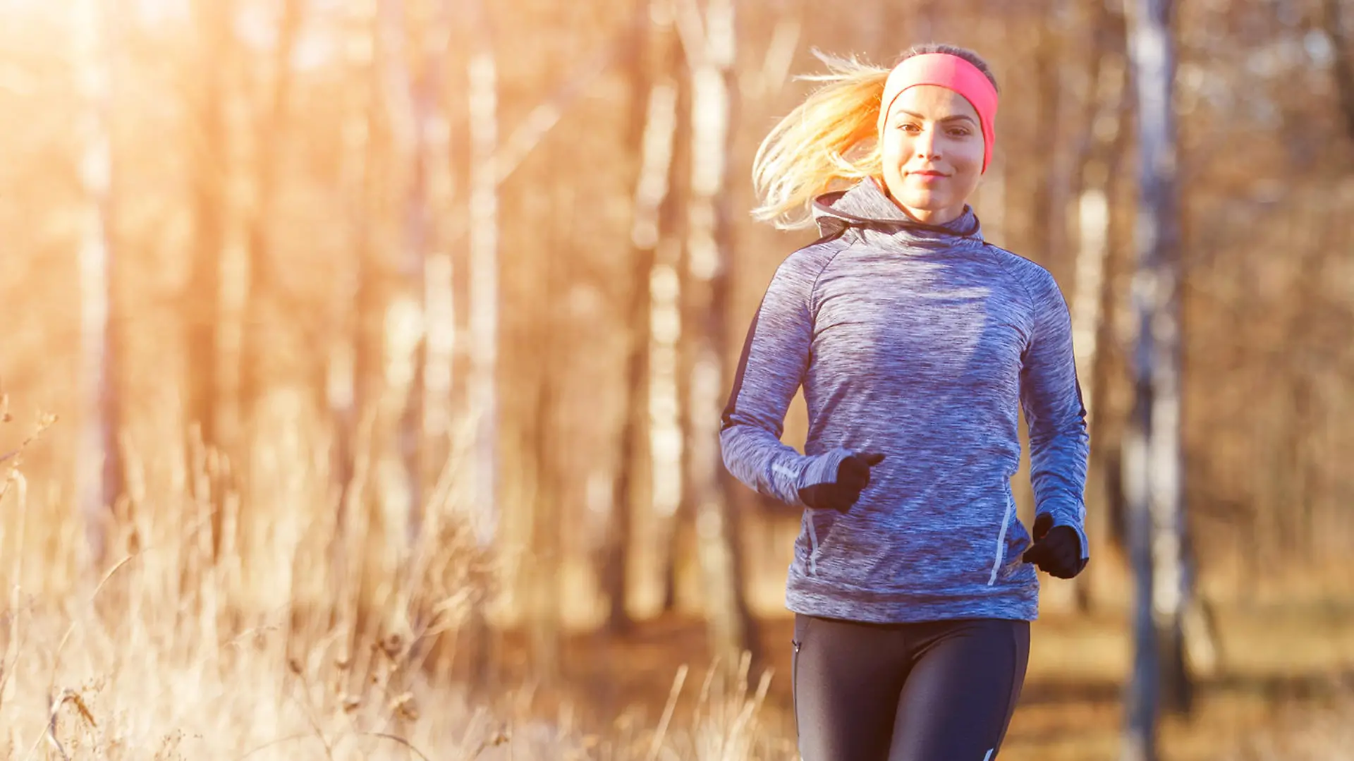 Young slim girl running in the park in early winter. Attractive woman jogging on snowy trail