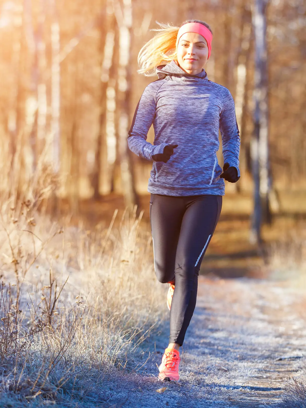 Young slim girl running in the park in early winter. Attractive woman jogging on snowy trail