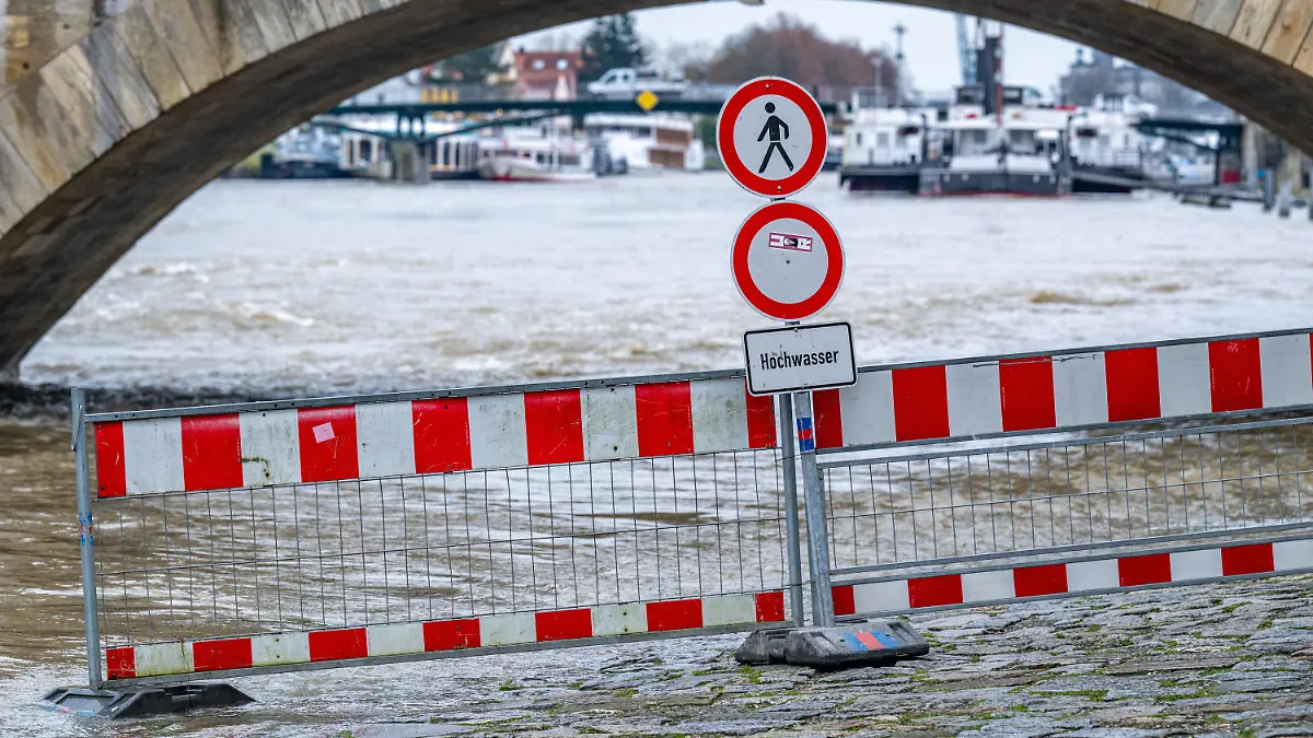 21.11.2023, Bayern, Regensburg: Ein Schild warnt an der Steinernen Brücke vor Hochwasser an der Donau. Foto: Armin Weigel/dpa +++ dpa-Bildfunk +++