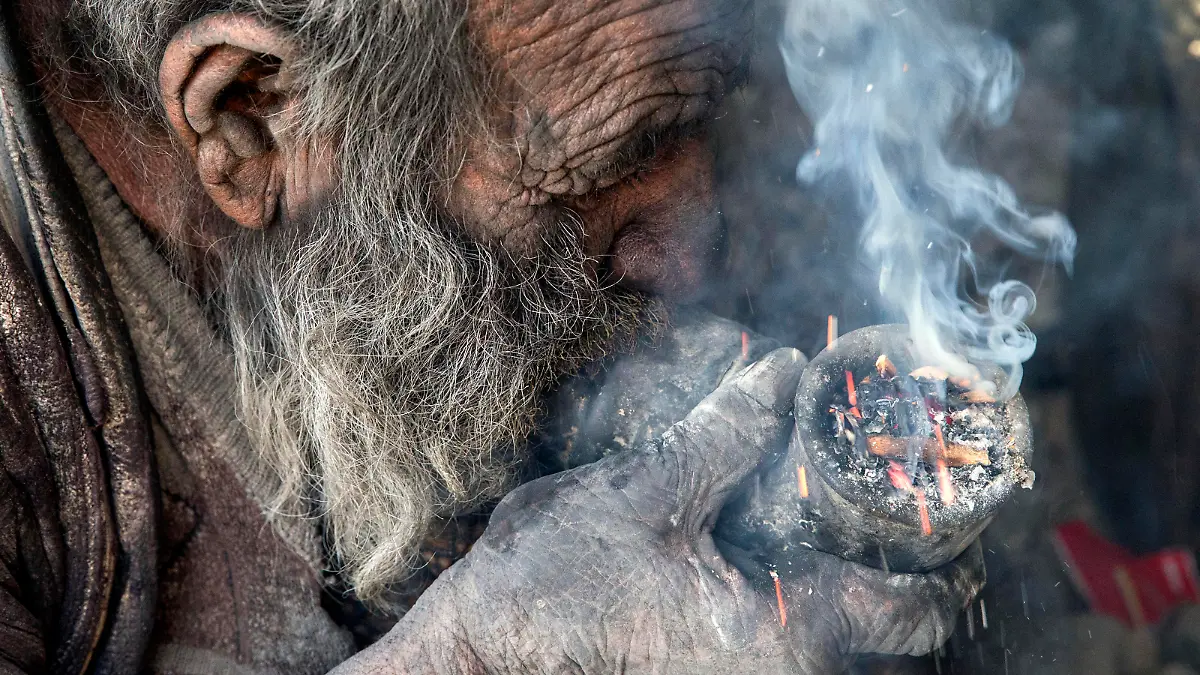 Amou Haji (uncle Haji) smokes from his waterpipe as he sits on the ground on the outskirts of the village of Dezhgah in the Dehram district of the southwestern Iranian Fars province, on December 28, 2018. - Believed to be the worlds dirtiest man, villagers say that Haji's leather-like skin hasn't touched soap and water for more than sixty years. They believe that he decided to live in isolation after suffering from an emotional setback in his youth. (Photo by AFP)