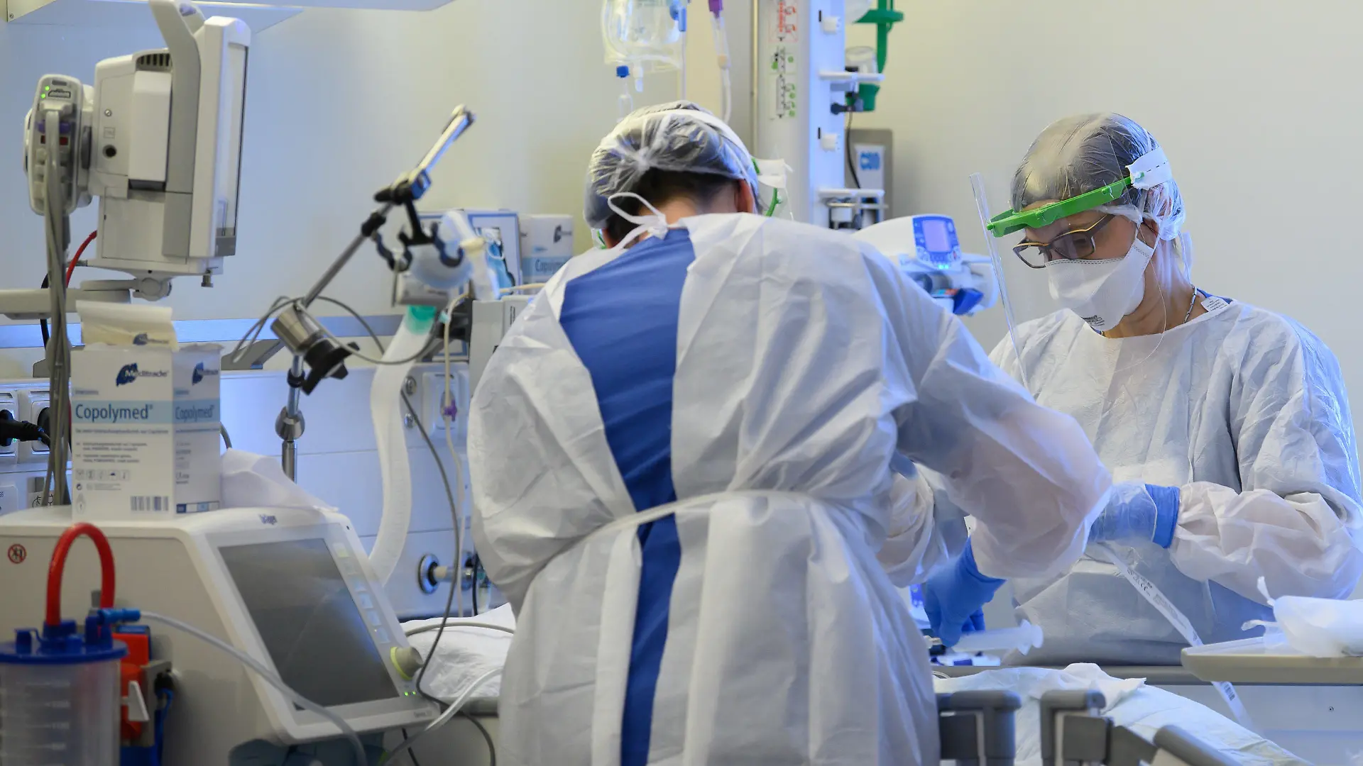 ARCHIV - 19.01.2021, Sachsen, Pulsnitz: Intensivpflegerinnen sind in Schutzkleidungen auf der Covid-19 Intensivstation einer Klinik mit der Versorgung von Corona-Patienten beschäftigt. Derzeit werden überdurchschnittlich hohe Personalausfälle in den Kliniken beklagt. Fast drei Viertel der Krankenhäuser berichten von höheren Personalausfällen in patientennahen Bereichen als um diese Jahreszeit üblich, wie aus einer Umfrage des Deutschen Krankenhausinstituts unter mehr als 240 Kliniken von Mitte der Woche hervorgeht. Foto: Robert Michael/dpa-Zentralbild/dpa +++ dpa-Bildfunk +++