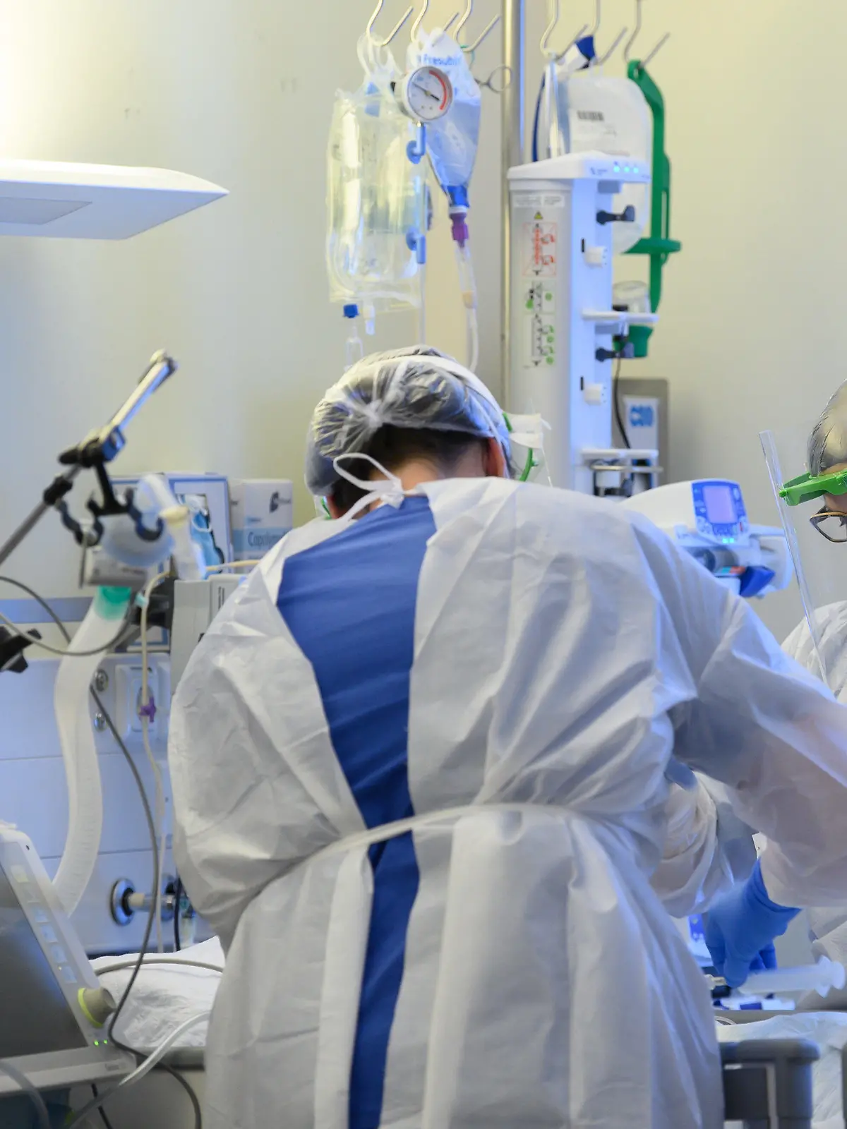 ARCHIV - 19.01.2021, Sachsen, Pulsnitz: Intensivpflegerinnen sind in Schutzkleidungen auf der Covid-19 Intensivstation einer Klinik mit der Versorgung von Corona-Patienten beschäftigt. Derzeit werden überdurchschnittlich hohe Personalausfälle in den Kliniken beklagt. Fast drei Viertel der Krankenhäuser berichten von höheren Personalausfällen in patientennahen Bereichen als um diese Jahreszeit üblich, wie aus einer Umfrage des Deutschen Krankenhausinstituts unter mehr als 240 Kliniken von Mitte der Woche hervorgeht. Foto: Robert Michael/dpa-Zentralbild/dpa +++ dpa-Bildfunk +++