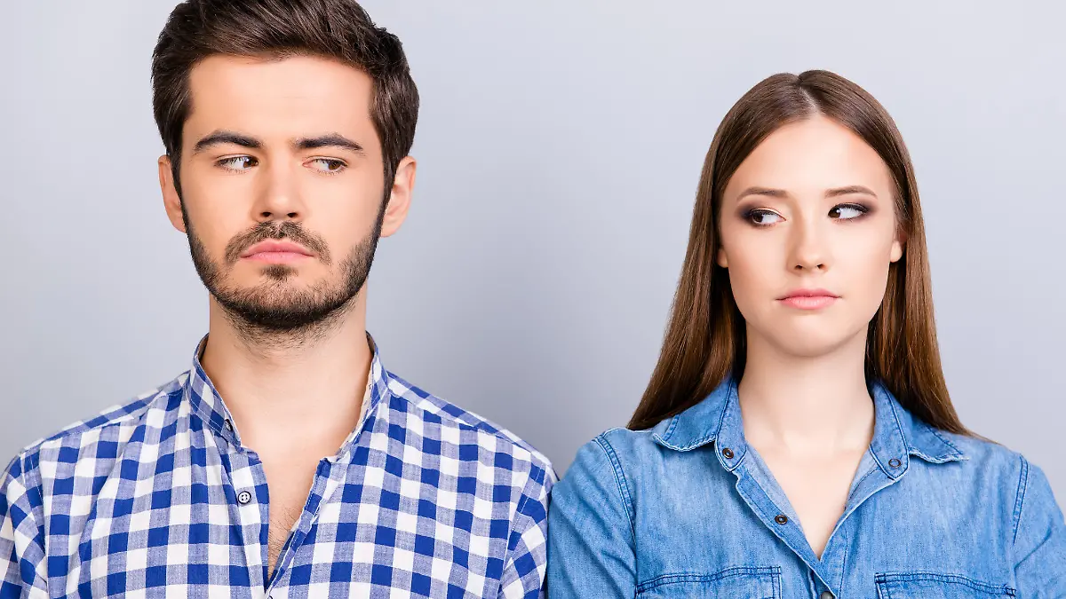 Mistrust and cheat problems. Annoyed couple is ignoring each other, but spy each other secretly, they stand on pure background in casual shirts