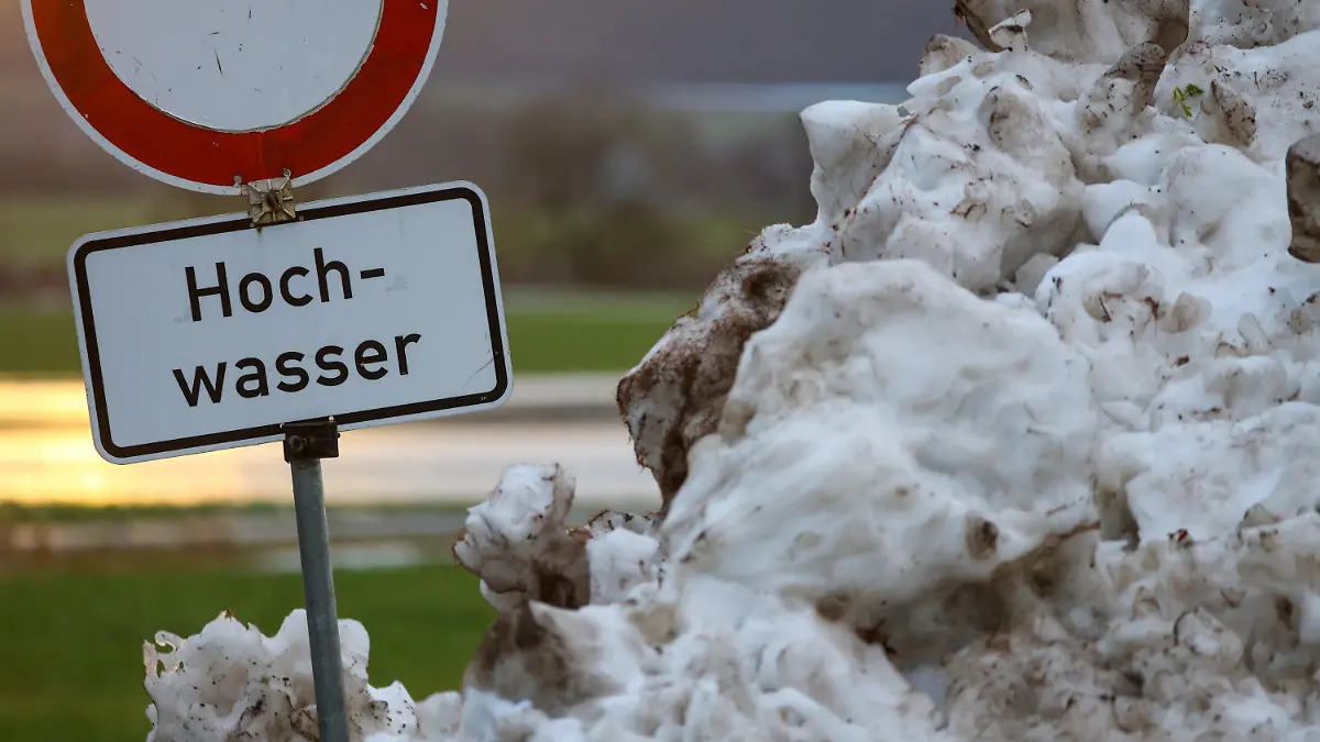 10.12.2023, Baden-Württemberg, Riedlingen: Neben einem Schneehaufen steht an der Donau ein Schild mit der Aufschrift "Hochwasser". Die milderen Temperaturen, anhaltender Regen und schmelzender Schnee erhöhen vielerorts die Hochwassergefahr. Foto: Thomas Warnack/dpa +++ dpa-Bildfunk +++