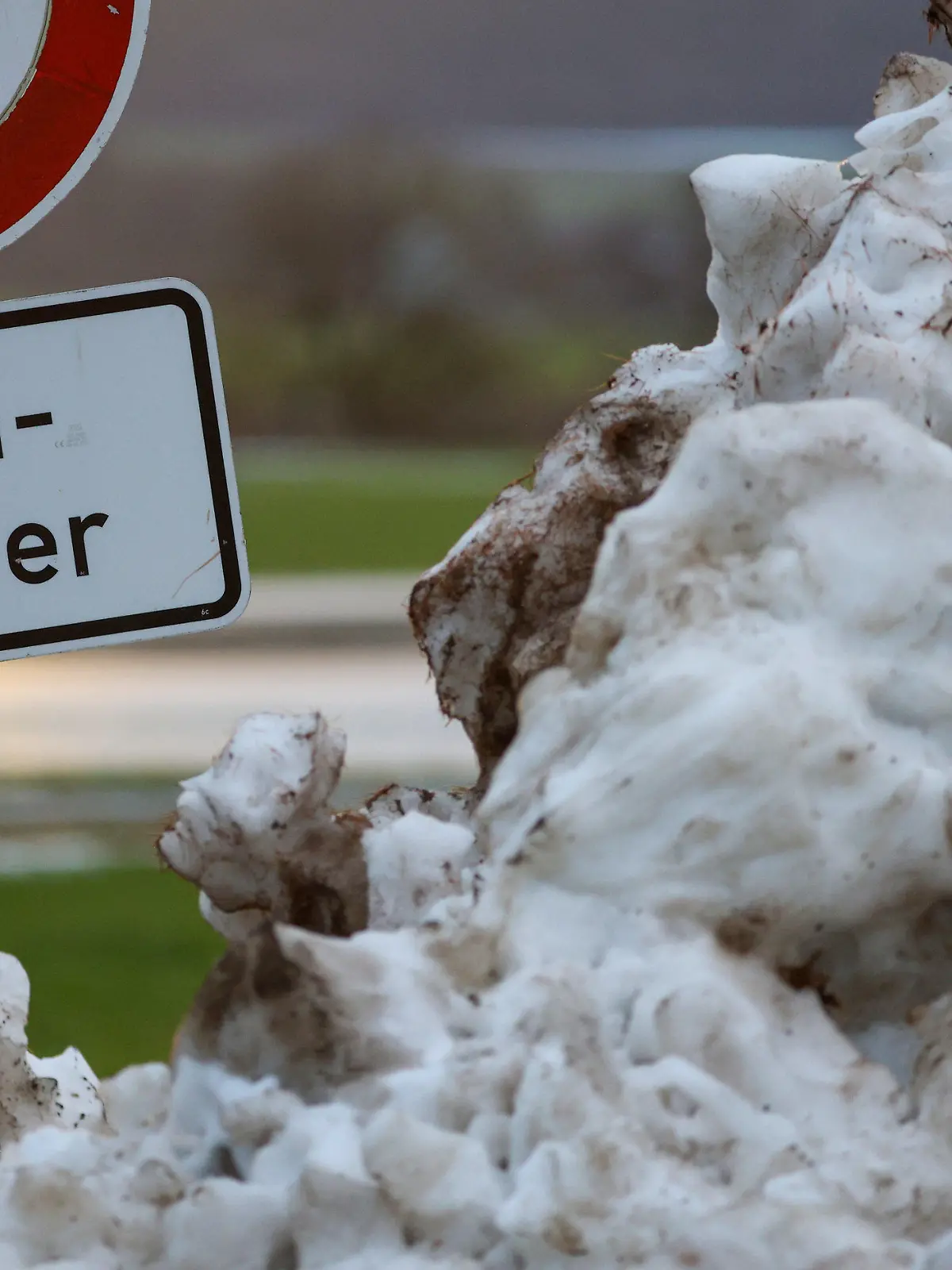10.12.2023, Baden-Württemberg, Riedlingen: Neben einem Schneehaufen steht an der Donau ein Schild mit der Aufschrift "Hochwasser". Die milderen Temperaturen, anhaltender Regen und schmelzender Schnee erhöhen vielerorts die Hochwassergefahr. Foto: Thomas Warnack/dpa +++ dpa-Bildfunk +++