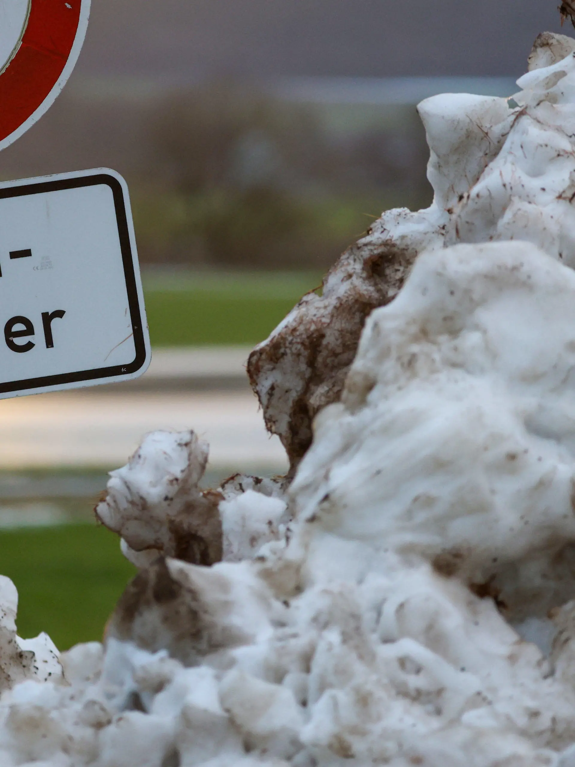 10.12.2023, Baden-Württemberg, Riedlingen: Neben einem Schneehaufen steht an der Donau ein Schild mit der Aufschrift "Hochwasser". Die milderen Temperaturen, anhaltender Regen und schmelzender Schnee erhöhen vielerorts die Hochwassergefahr. Foto: Thomas Warnack/dpa +++ dpa-Bildfunk +++