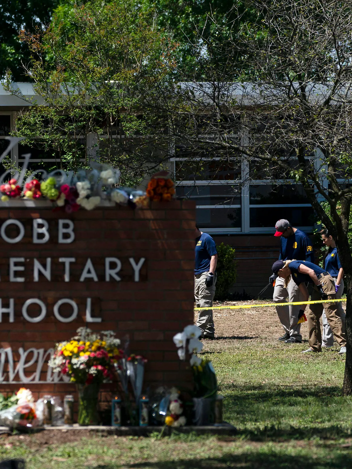 FILE - Investigators search for evidences outside Robb Elementary School in Uvalde, Texas, May 25, 2022, after an 18-year-old gunman killed 19 students and two teachers.  Four months after the Robb Elementary School shooting, the Uvalde school district on Friday, Oct. 7 pulled its entire embattled campus police force off the job following a wave of new outrage over the hiring of a former Texas state trooper who was part of the hesitant law enforcement response as a gunman killed 19 children and two teachers.(AP Photo/Jae C. Hong, File)