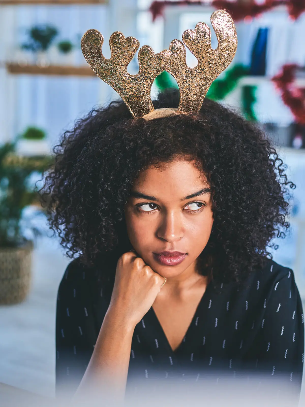 Cropped shot of an attractive young businesswoman sitting alone in her office and looking bored while wearing christmas headgear