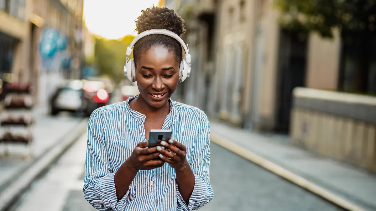 African American woman in the city, wearing headphones and using smart phone