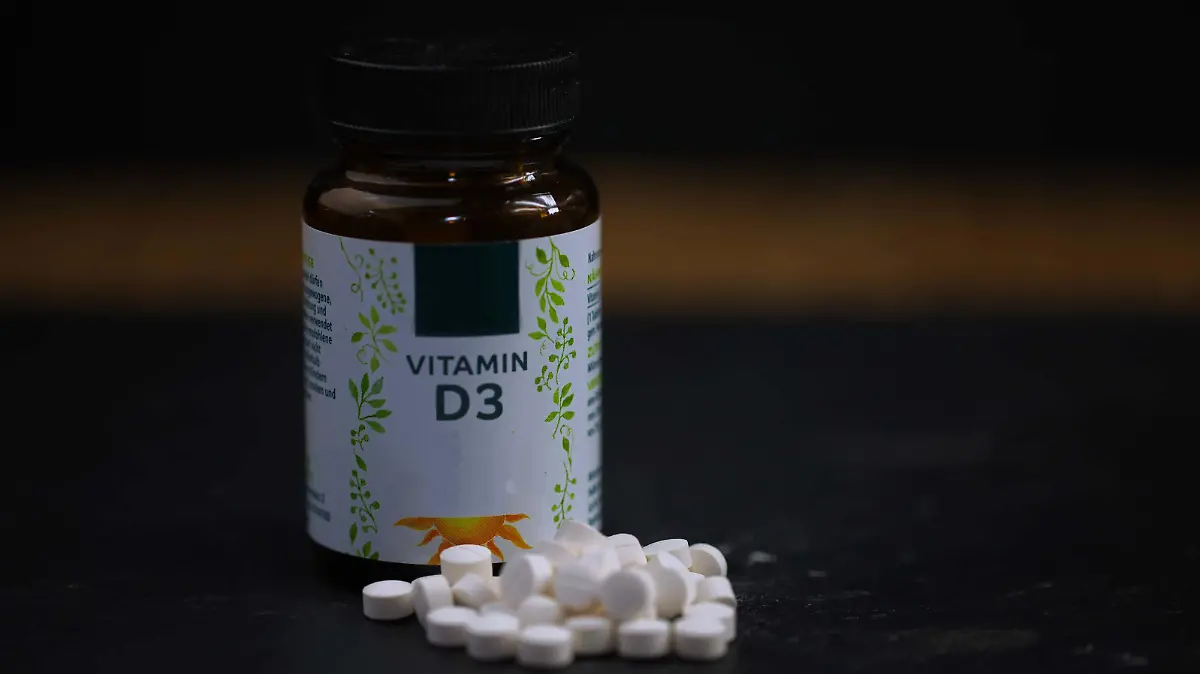 Vitamin D Tabletten vor einem Medikamenten-Glas