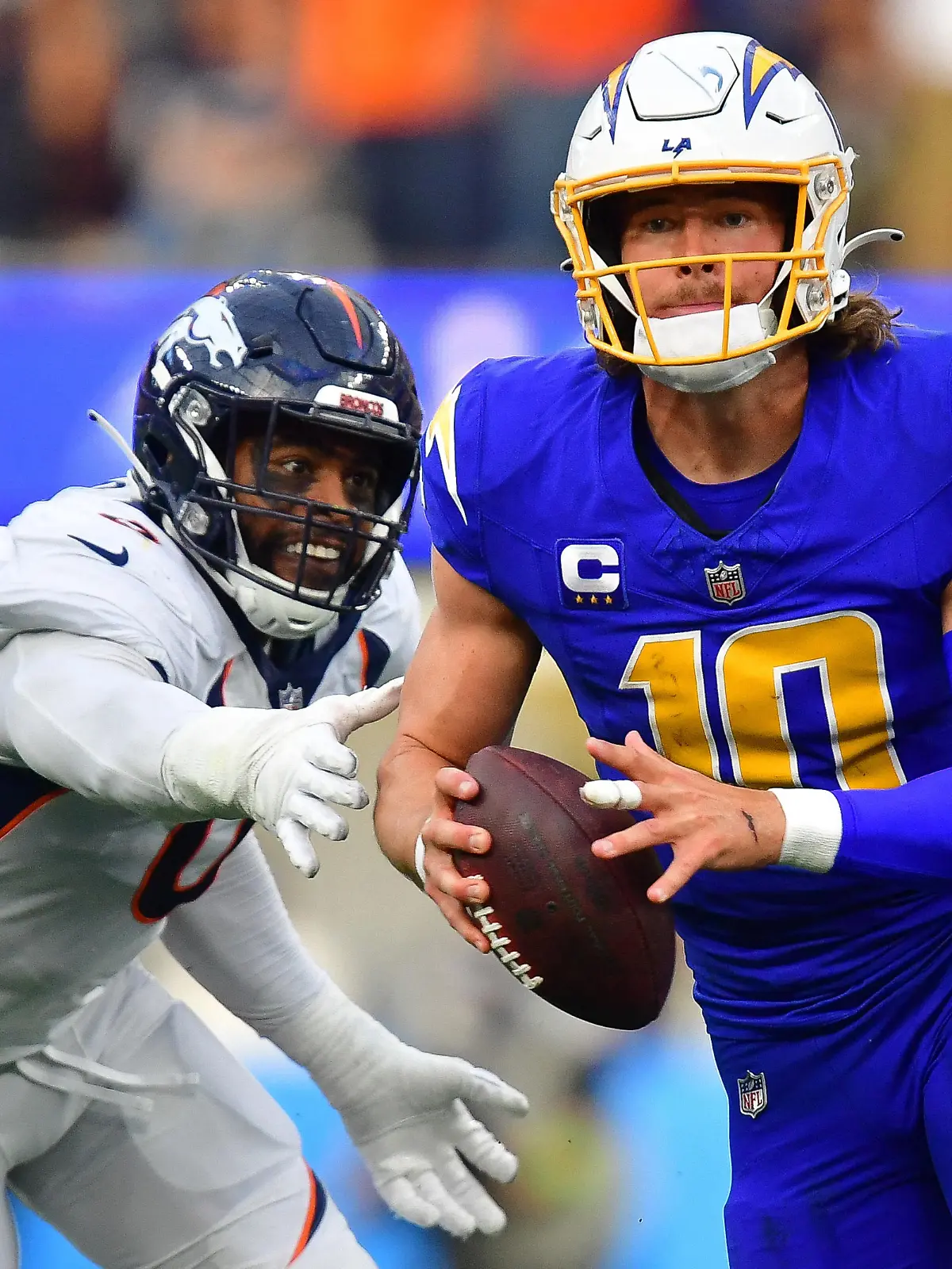 Dec 10, 2023; Inglewood, California, USA; Los Angeles Chargers quarterback Justin Herbert (10) moves out to pass against the defense of Denver Broncos linebacker Jonathon Cooper (0) during the first half at SoFi Stadium. Mandatory Credit: Gary A. Vasquez-USA TODAY Sports