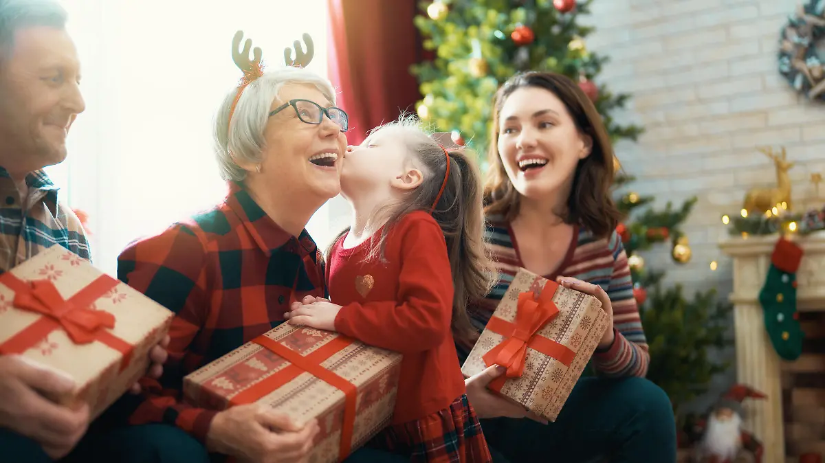 Merry Christmas and Happy Holidays! Grandma, grandpa, mum and child exchanging gifts. Parents and daughters having fun near tree indoors. Loving family with presents in room.