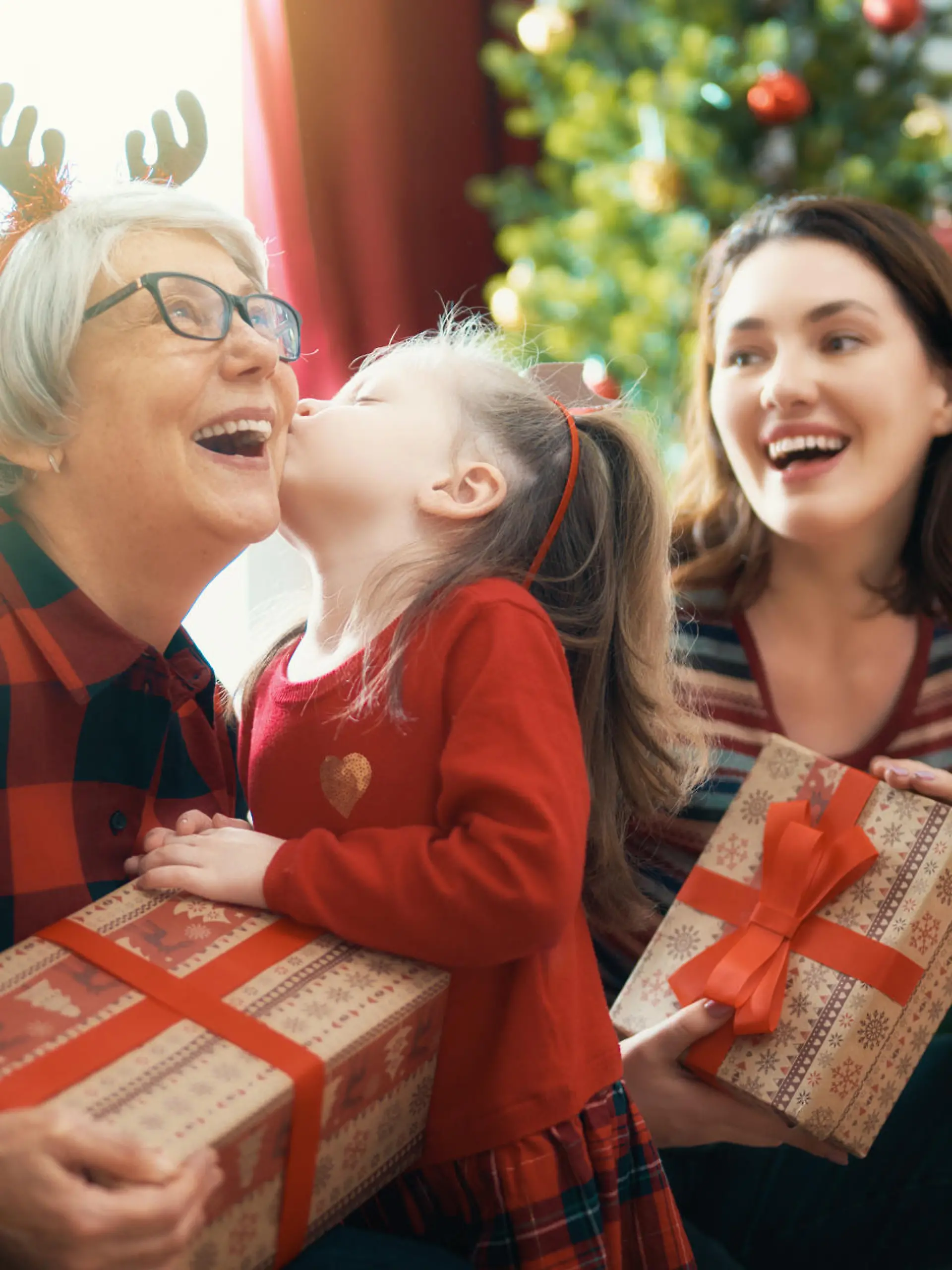                                 Merry Christmas and Happy Holidays! Grandma, grandpa, mum and child exchanging gifts. Parents and daughters having fun near tree indoors. Loving family with presents in room.