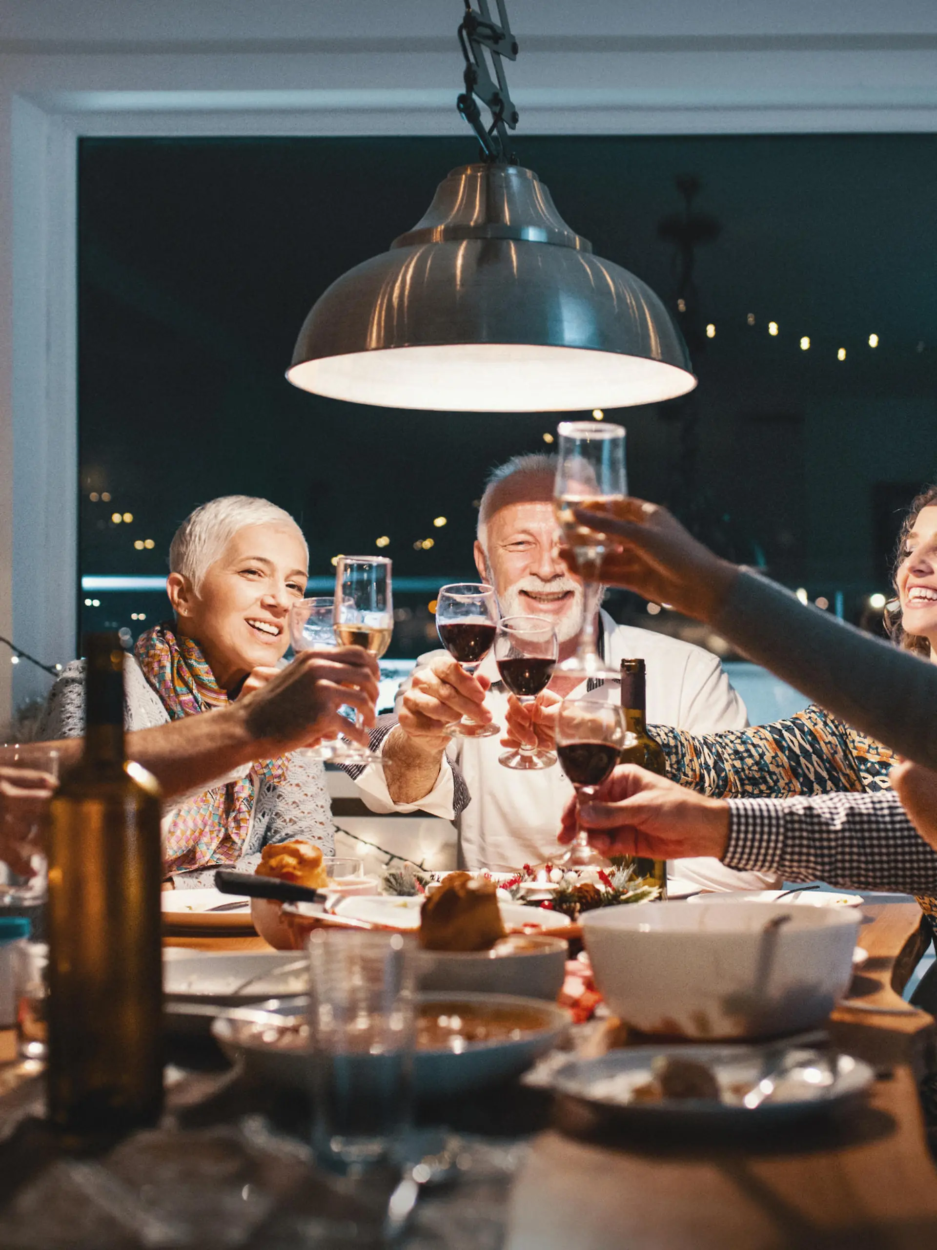Closeup side view of a family having a Christmas eve dinner. They are having some traditional roast, gravy and vegetables and also some vegetarian food. There are three men and four women at the table having casual conversation.