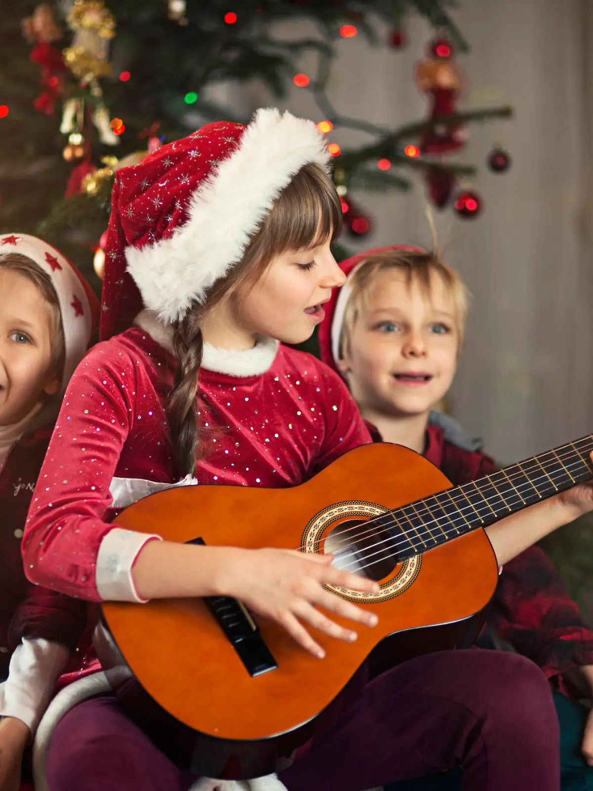 Kinder singen unter dem Weihnachtsbaum