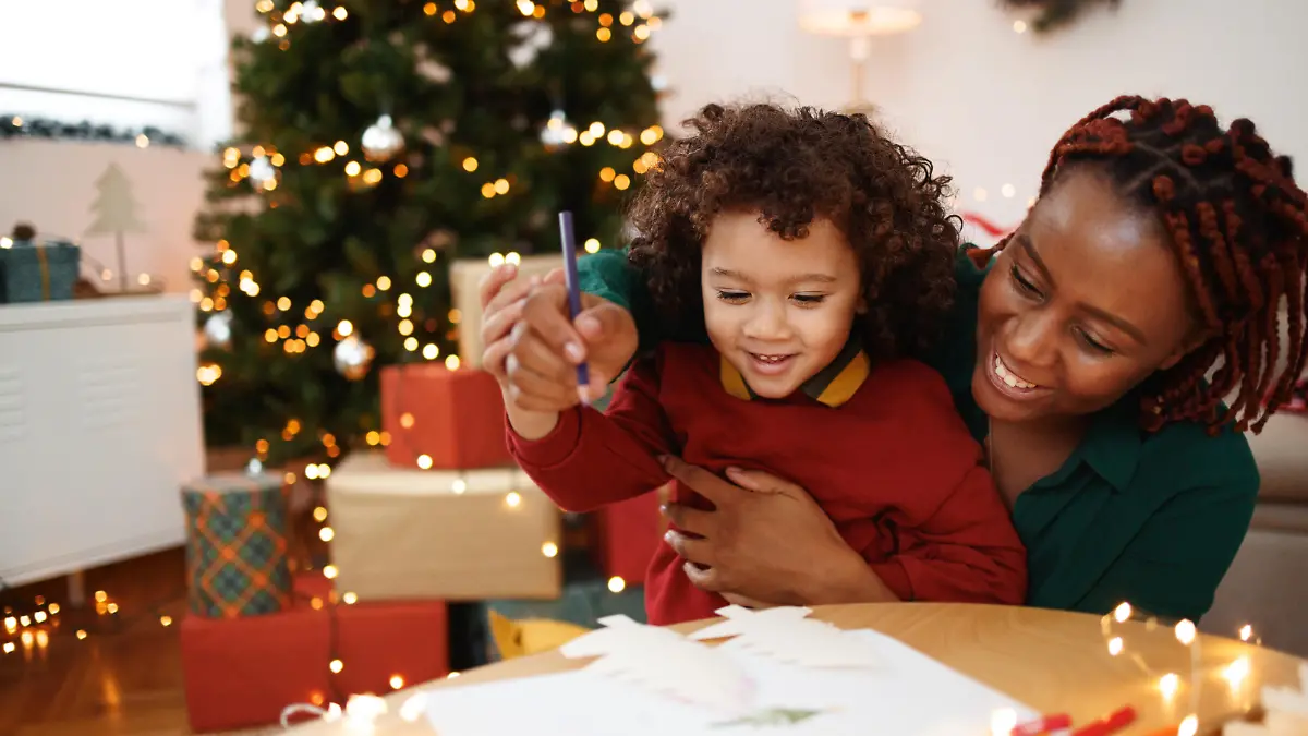 Mother and cute little son drawing together at the apartment during christams time