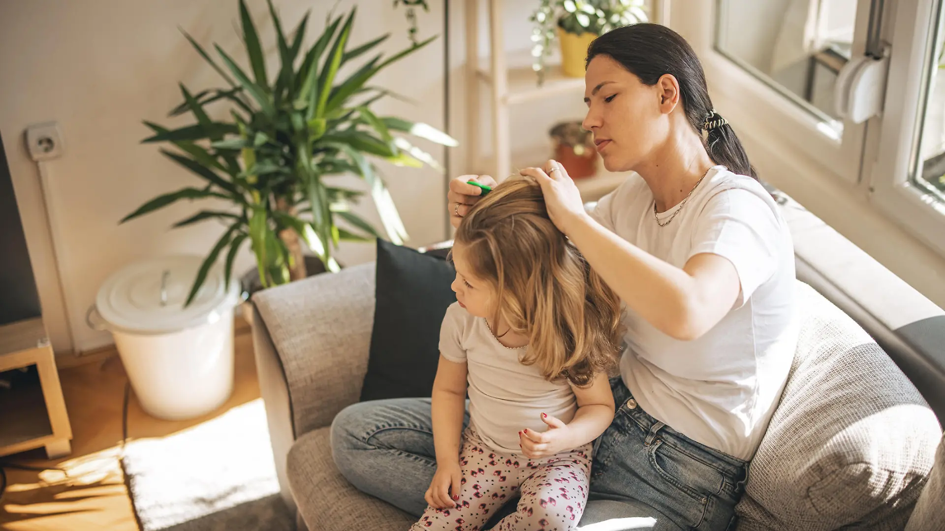 Mother doing head lice cleaning on daughter at home