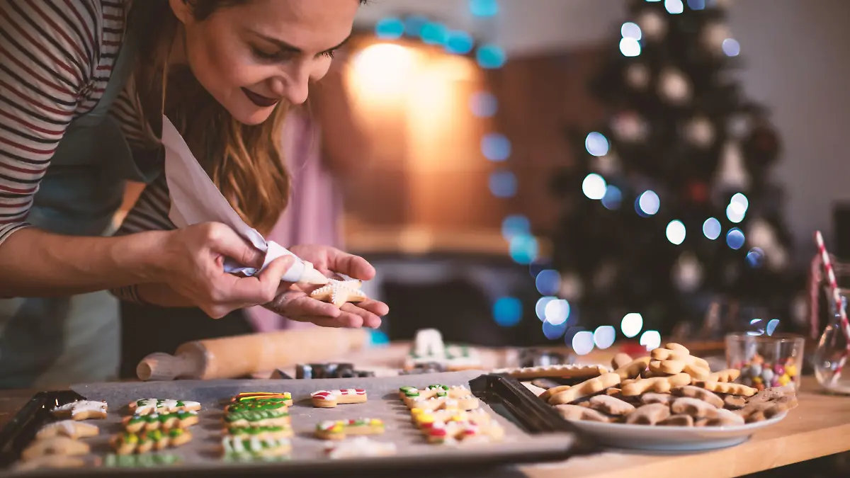 Young woman decorating a Gingerbread cookies for Christmas.