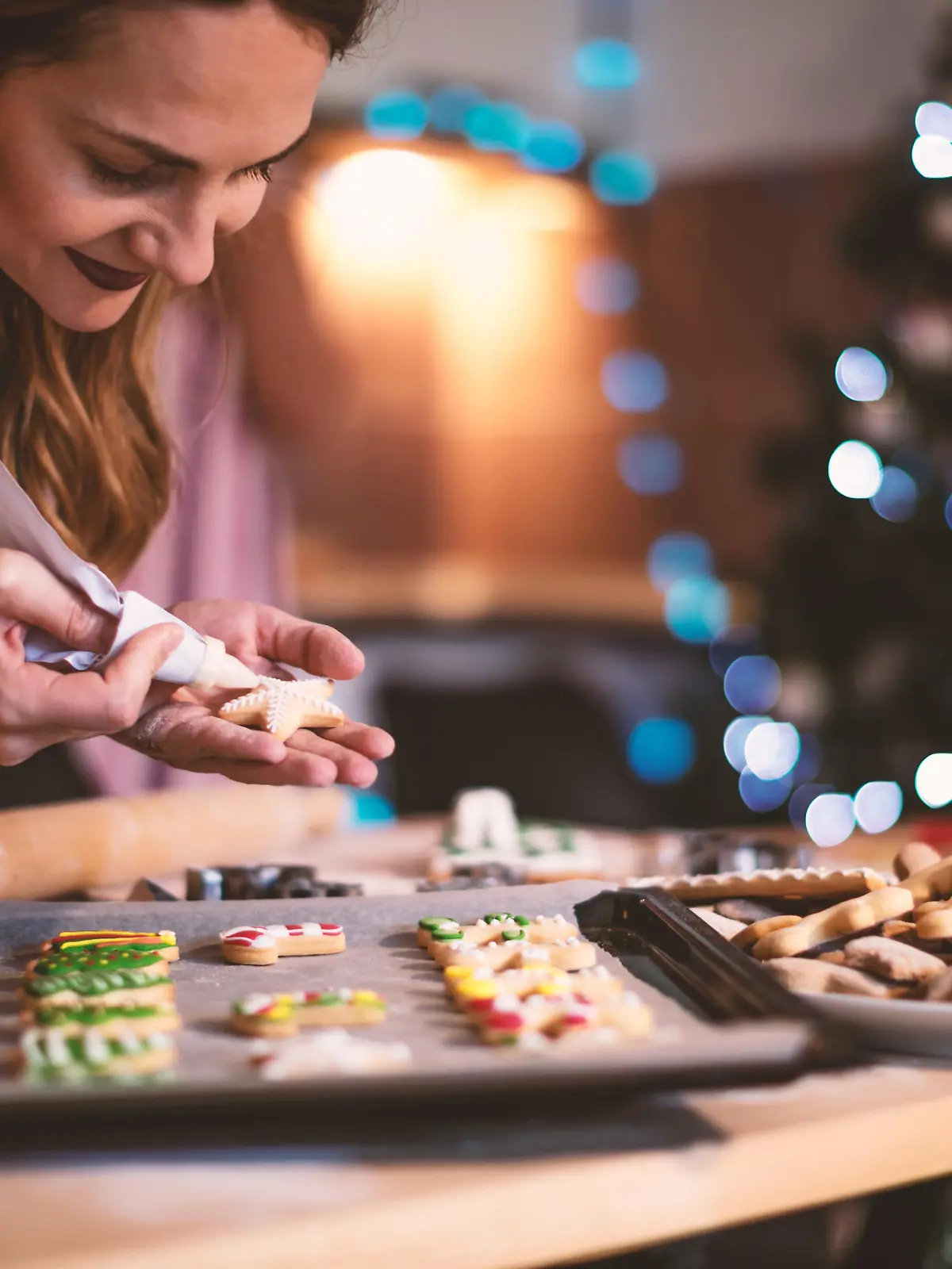 Young woman decorating a Gingerbread cookies for Christmas.