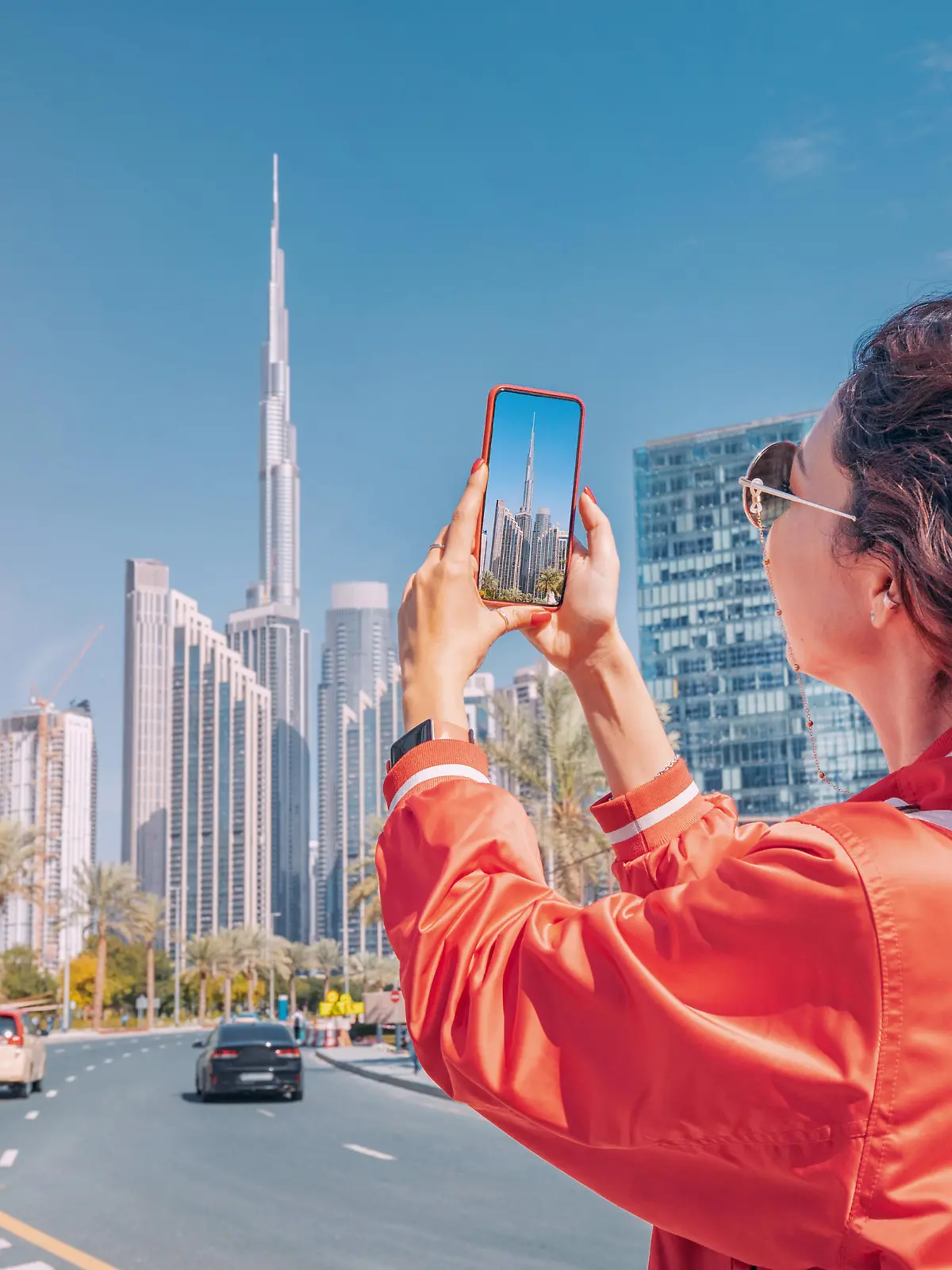Tourist happy girl taking photos for her travel blog, in Dubai downtown district against background of the Burj Khalifa highest skyscraper