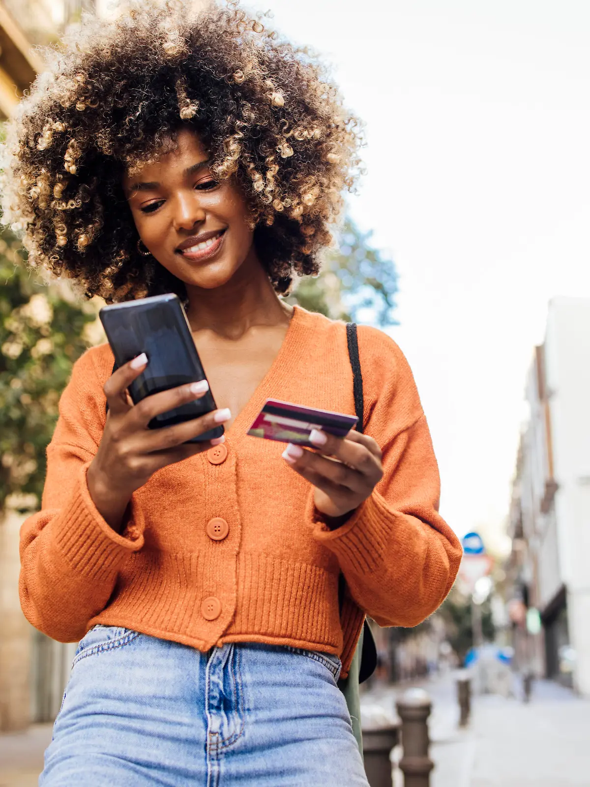 Portrait of a young African American woman on vacation in Barcelona shopping online on the street.