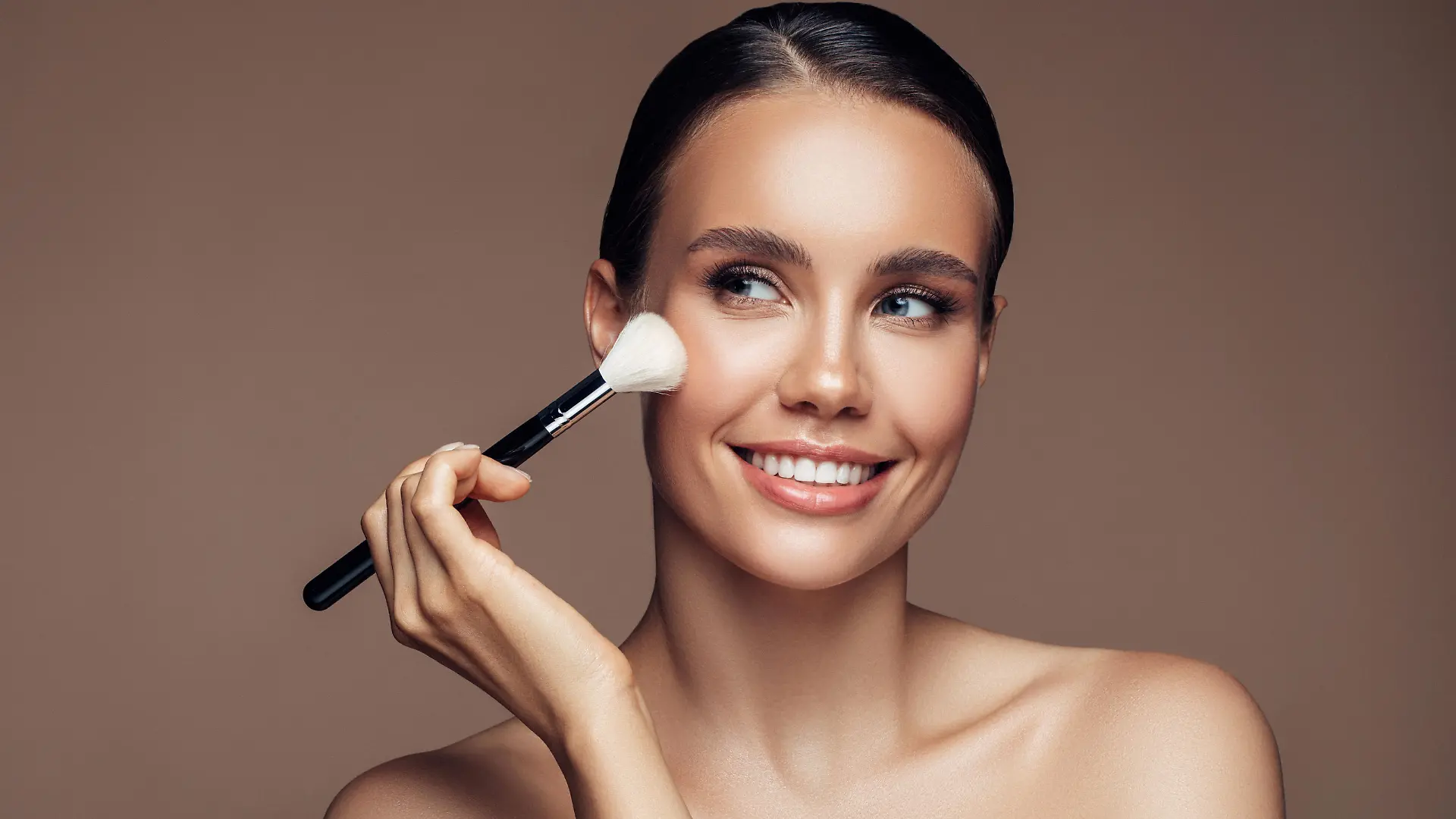 Beautiful young woman applying foundation powder